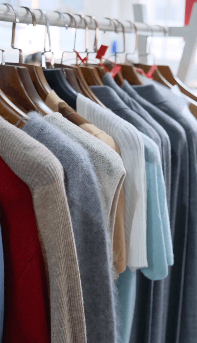 A rack of knitted sweater samples in assorted colors, showing knitwear style references and product development options for small-batch sourcing.