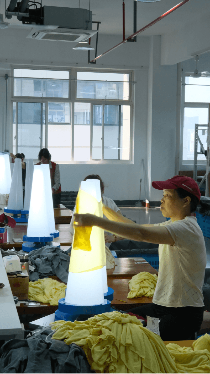 A knitted garment being checked on a light inspection station, showing finishing inspection and quality control before packing.