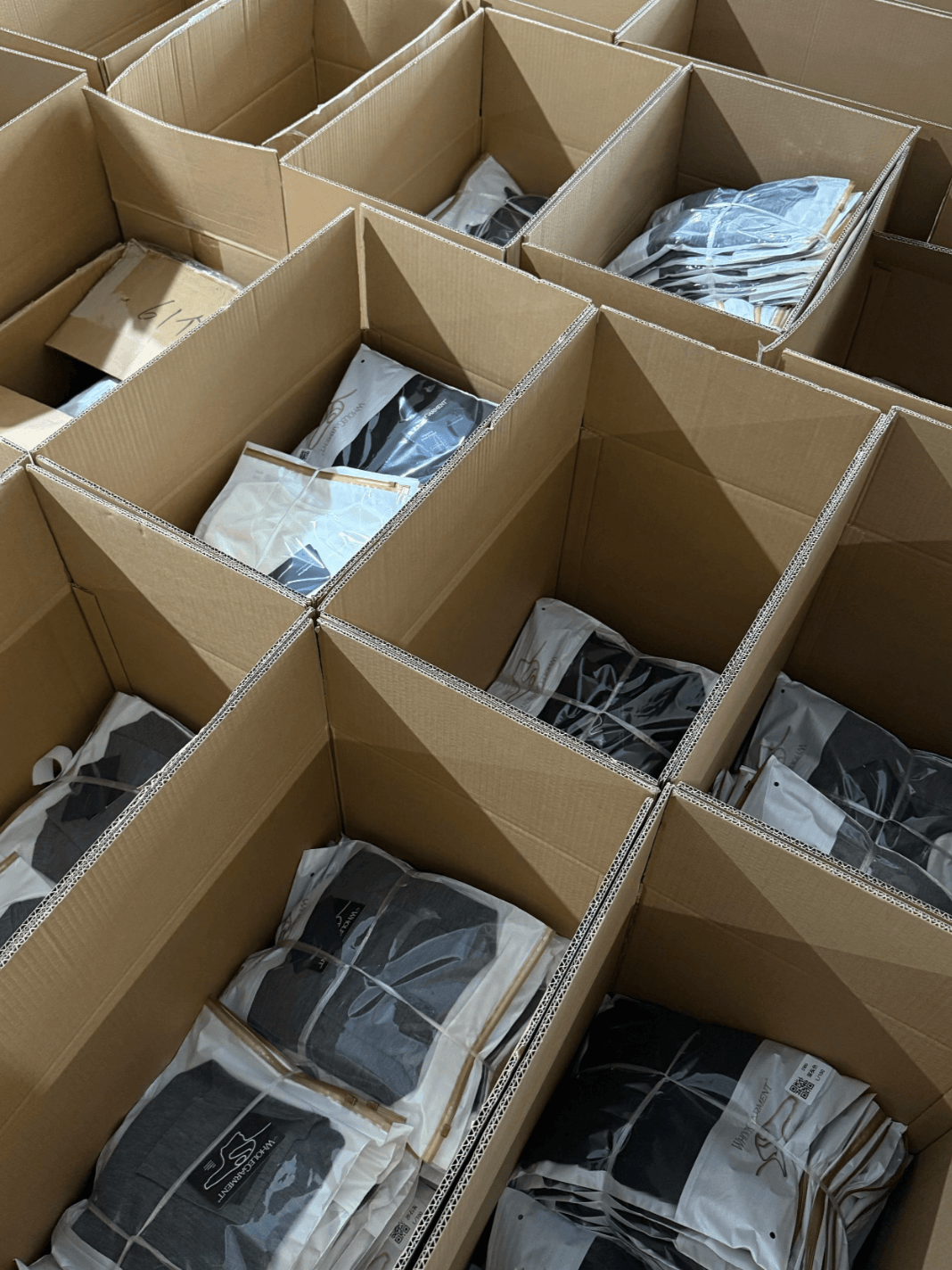 Individually packed knitwear pieces arranged in export cartons, showing the packing and delivery handover stage.