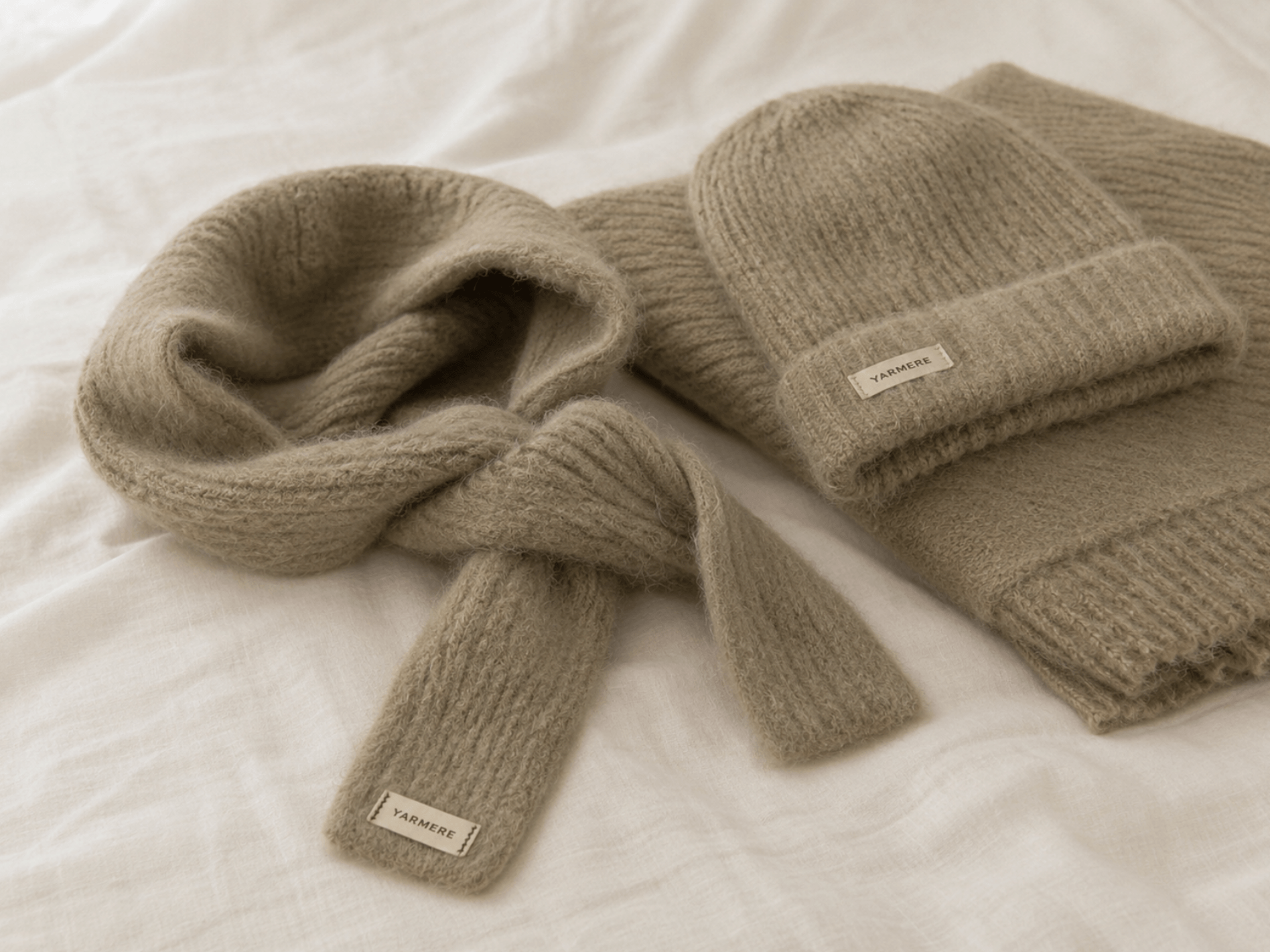 Soft beige knitted scarf and beanie set with brand labels, showing lightweight knit accessories for private label development.