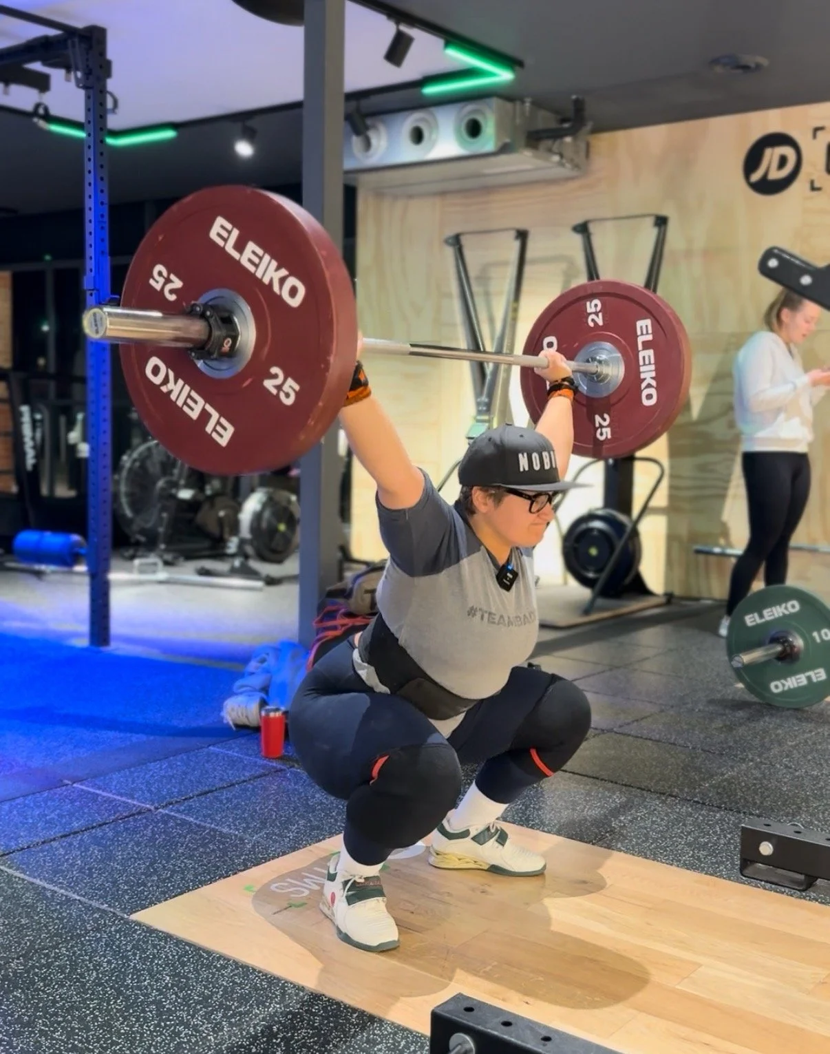 Yasmin doing a red plate overhead squat in the gym.