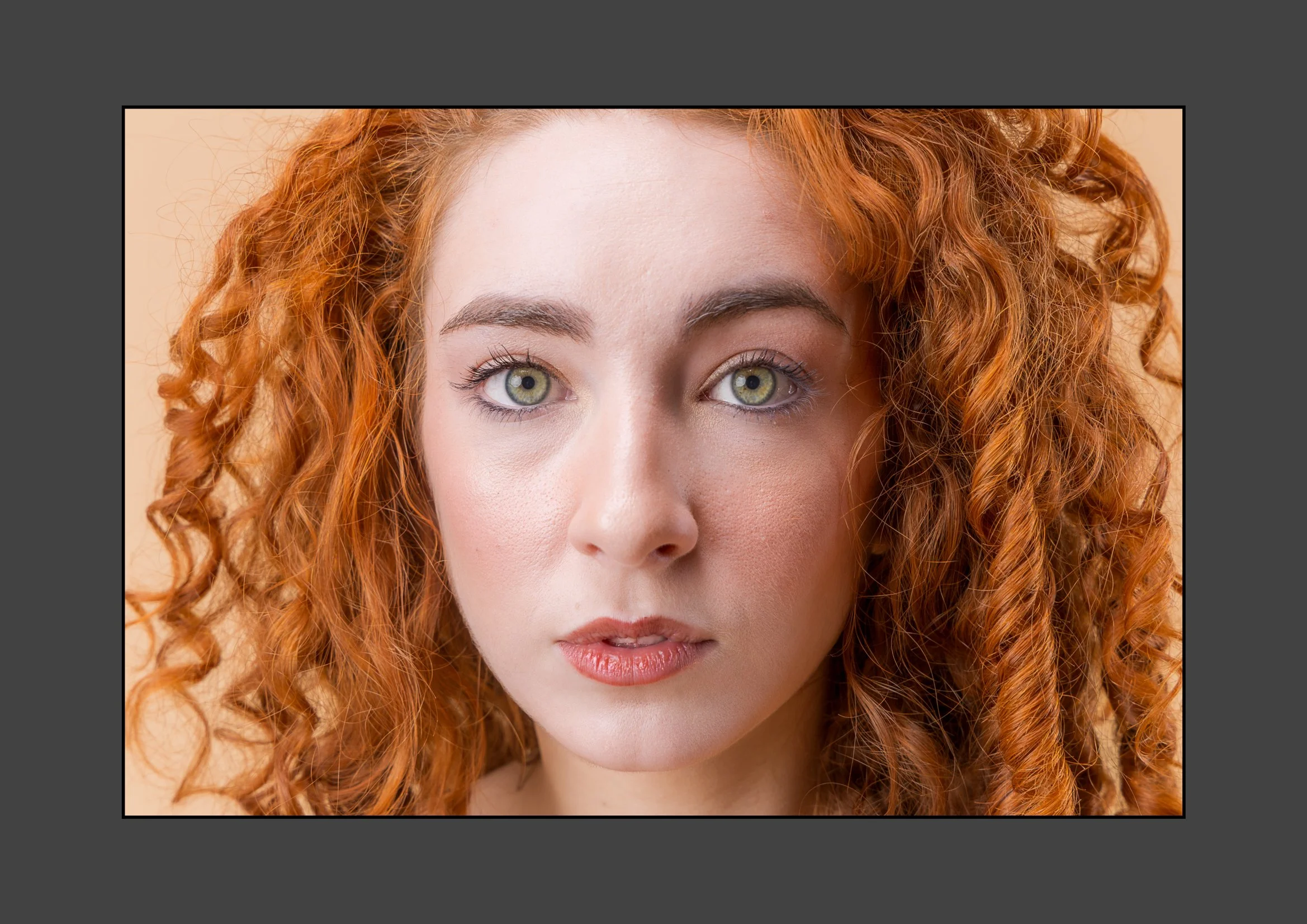 Close-up of a woman with curly red hair and light makeup.
