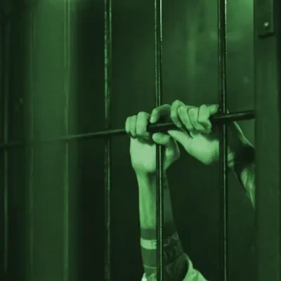 Person gripping a prison cell bar with hands through the bars. Escape Rooms Drogheda
