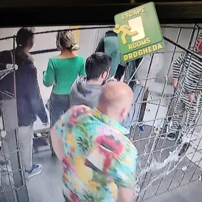 People waiting in line at an escape room with a sign that reads 'Escape Rooms Drogheda'.