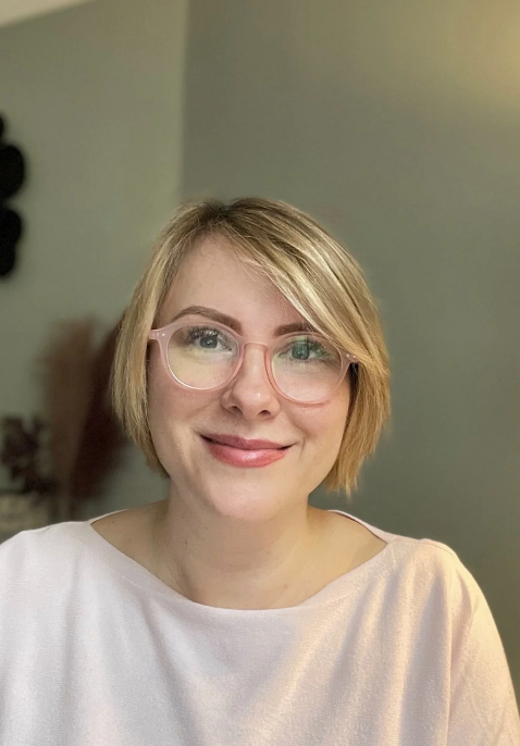 A smiling woman with blond hair and glasses.