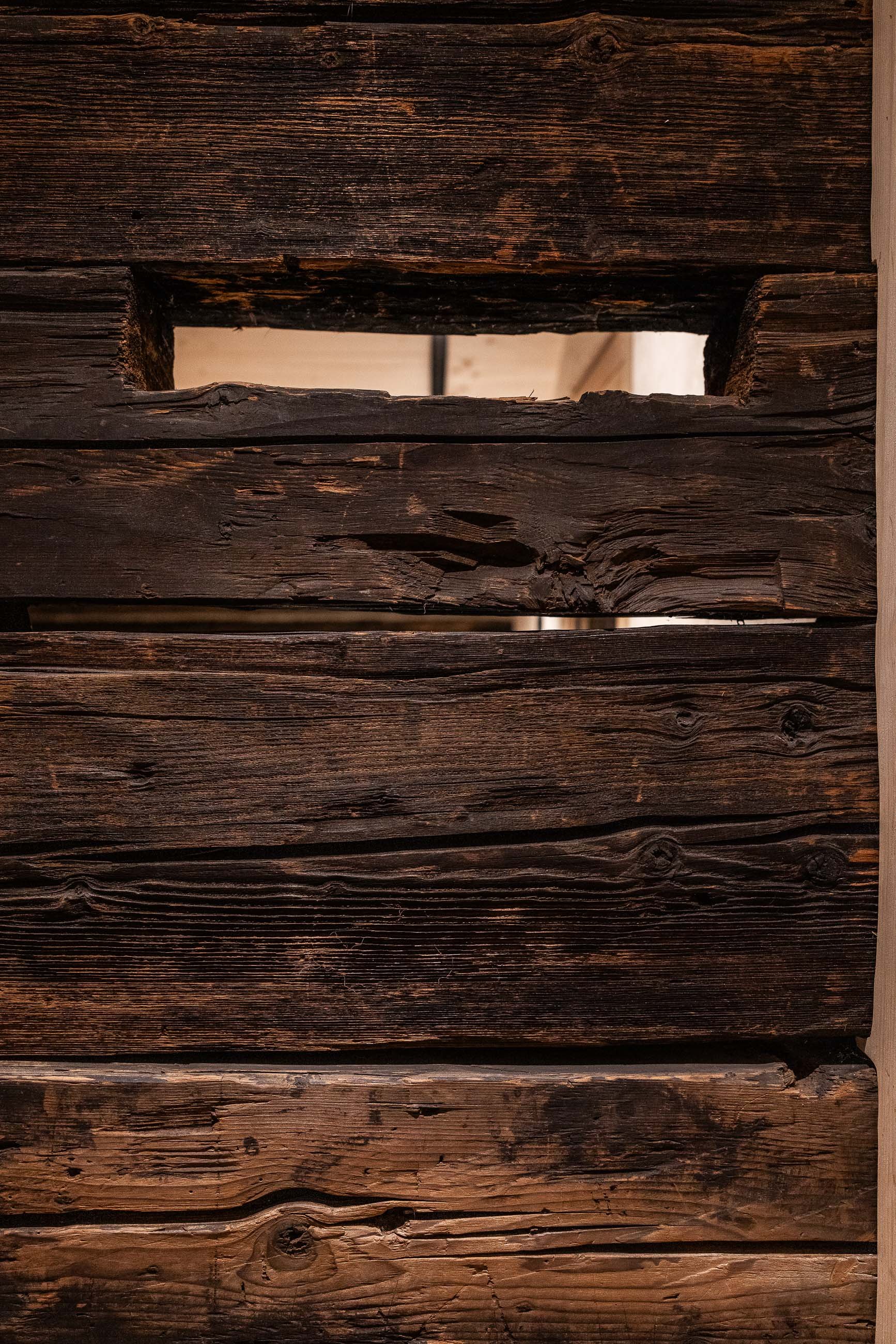 Nahaufnahme von dunklem, gealtertem Holz mit sichtbarer Maserung und Textur.