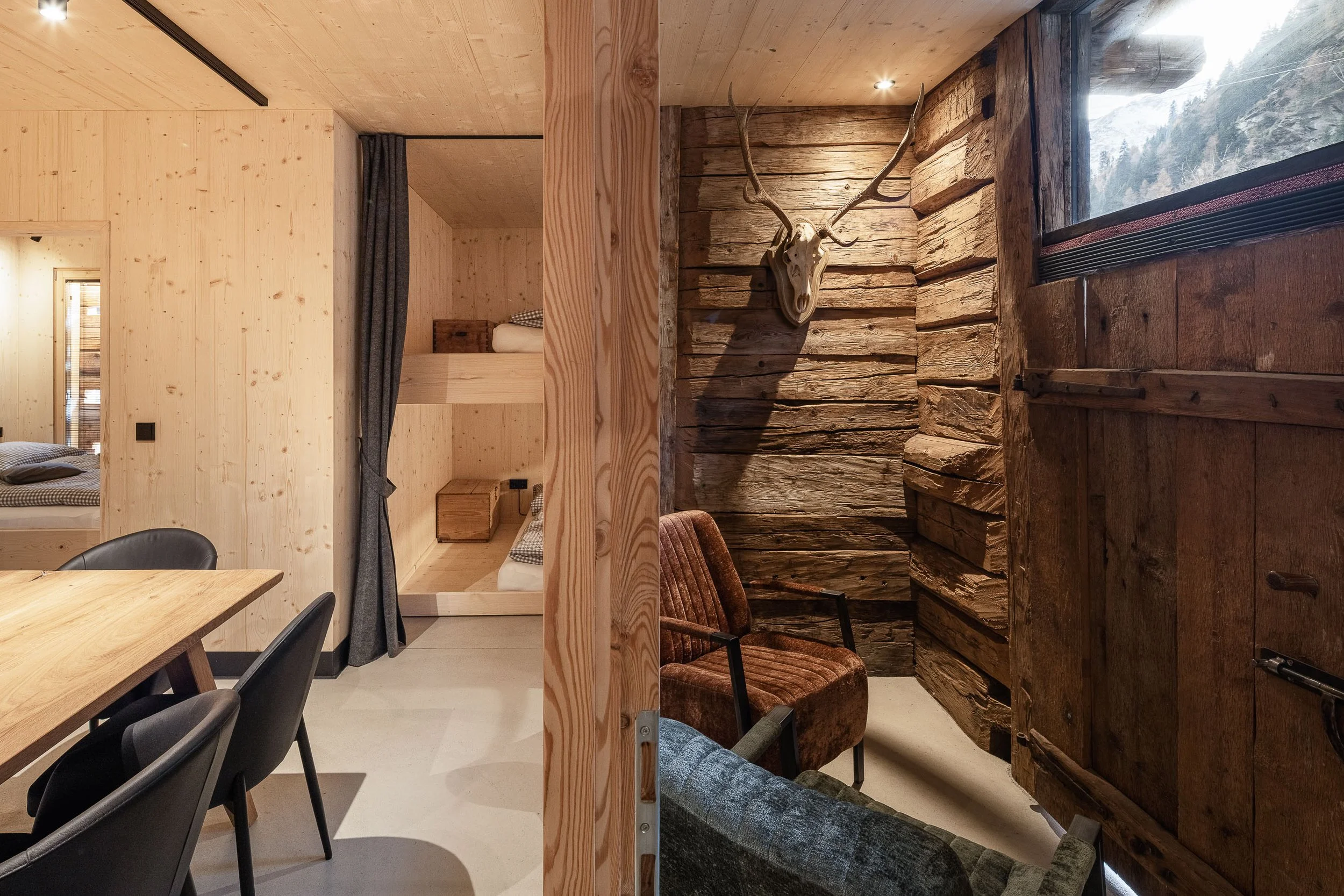 Inneneinrichtung eines Hauses mit Holzpaneelen, ein Hirschgeweih an der Wand und Sicht auf eine Berglandschaft durch ein Fenster.