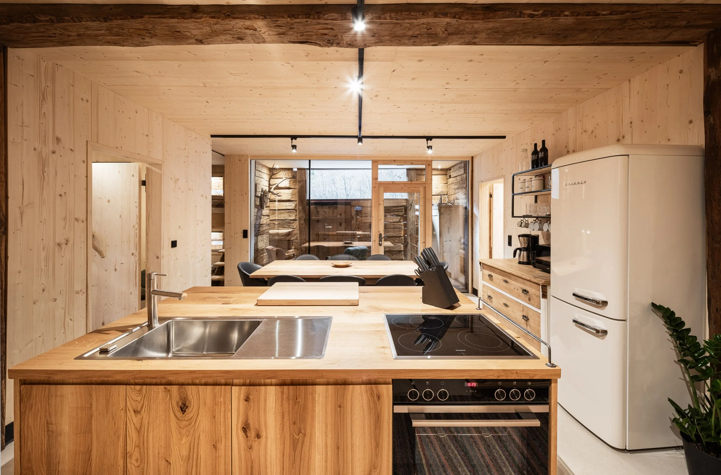 Moderne Küche mit Holzarbeitsplatte, Herd, Kühlschrank und Fenstern, in warmem Holzdesign.