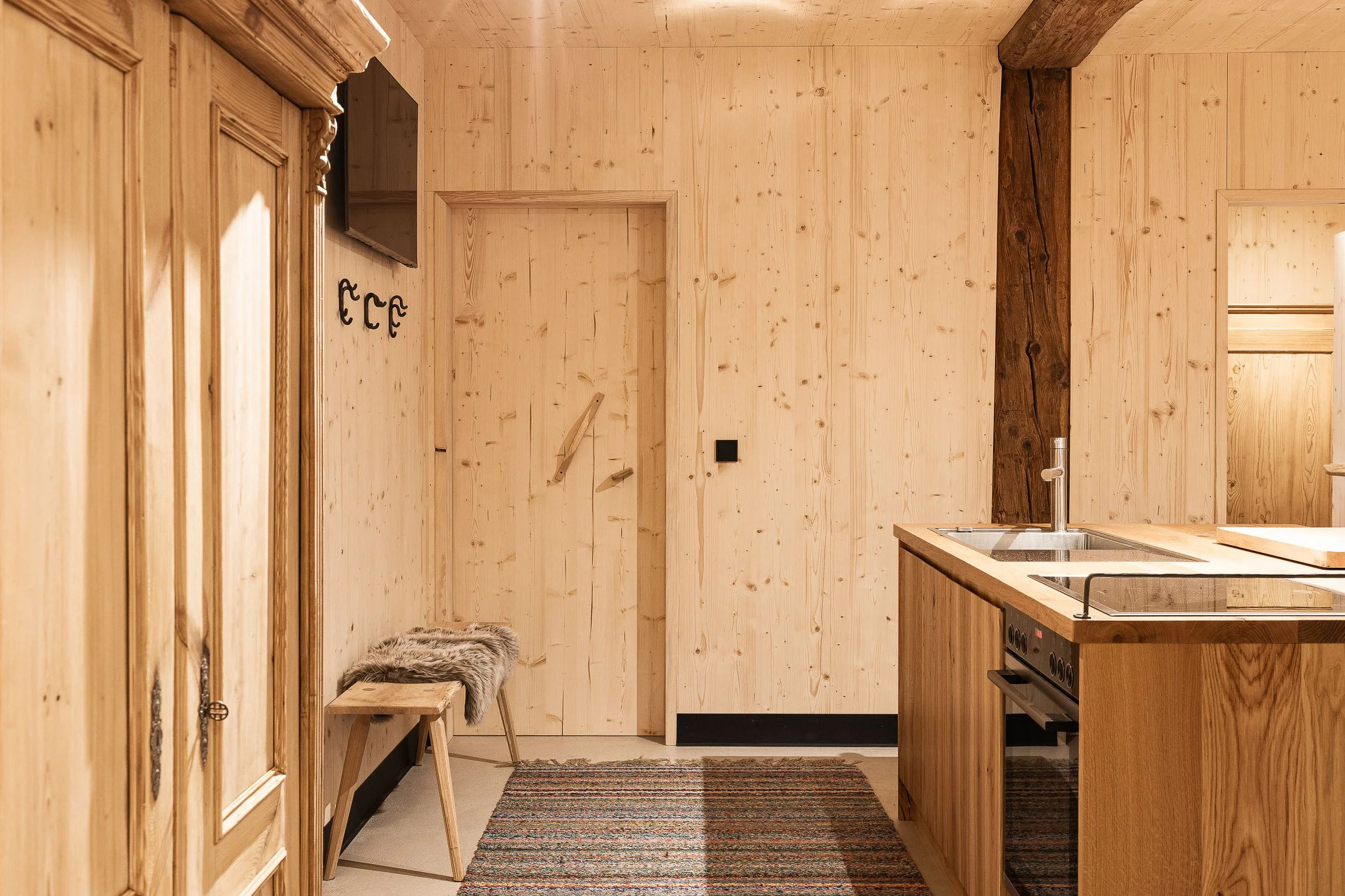 Küche mit Holzwänden, einem Herd, einem Waschbecken, einem kleinen Teppich und Haken an der Wand