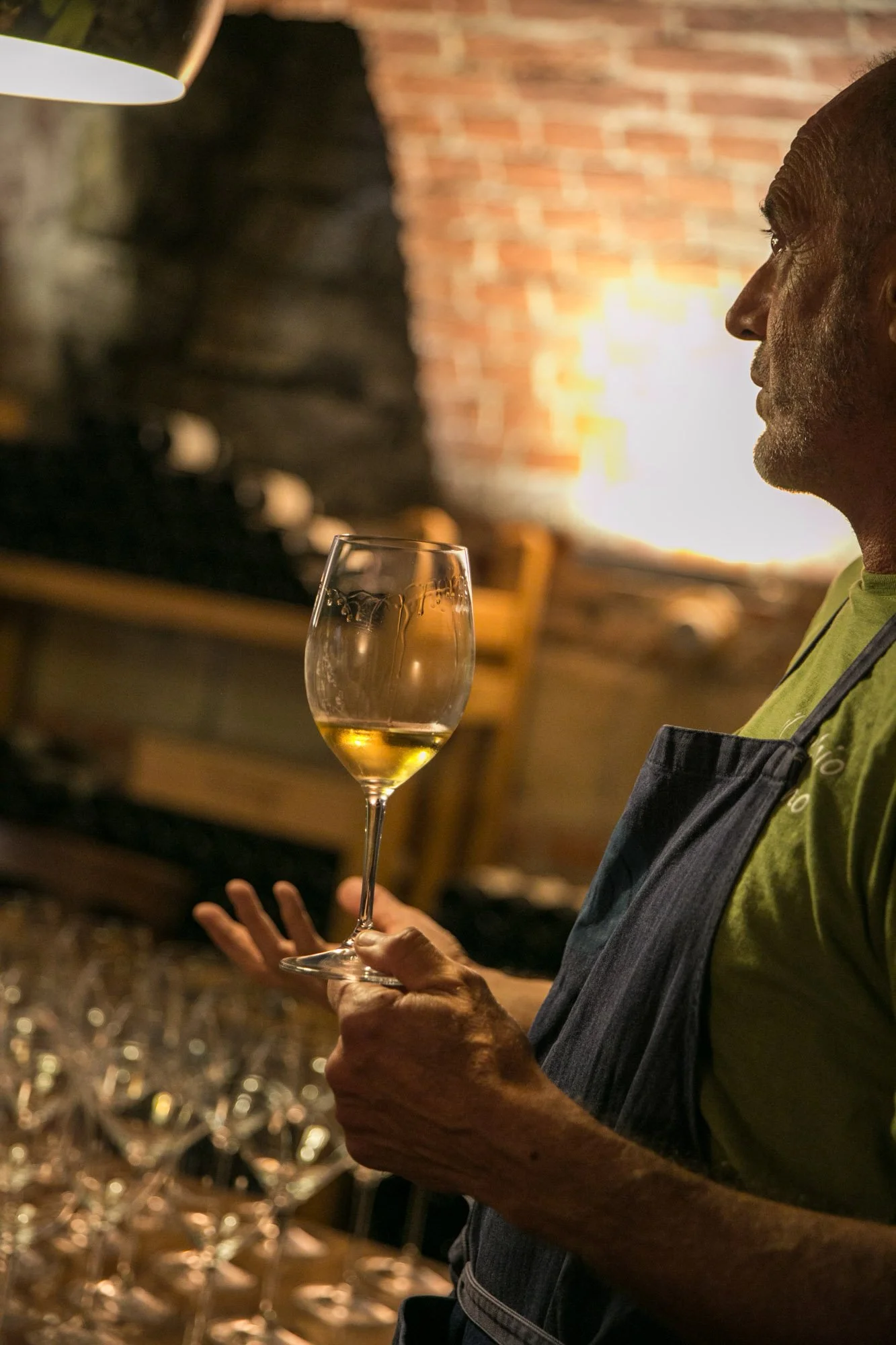 A person holding a wine glass in a dimly lit restaurant or bar with a brick wall background.