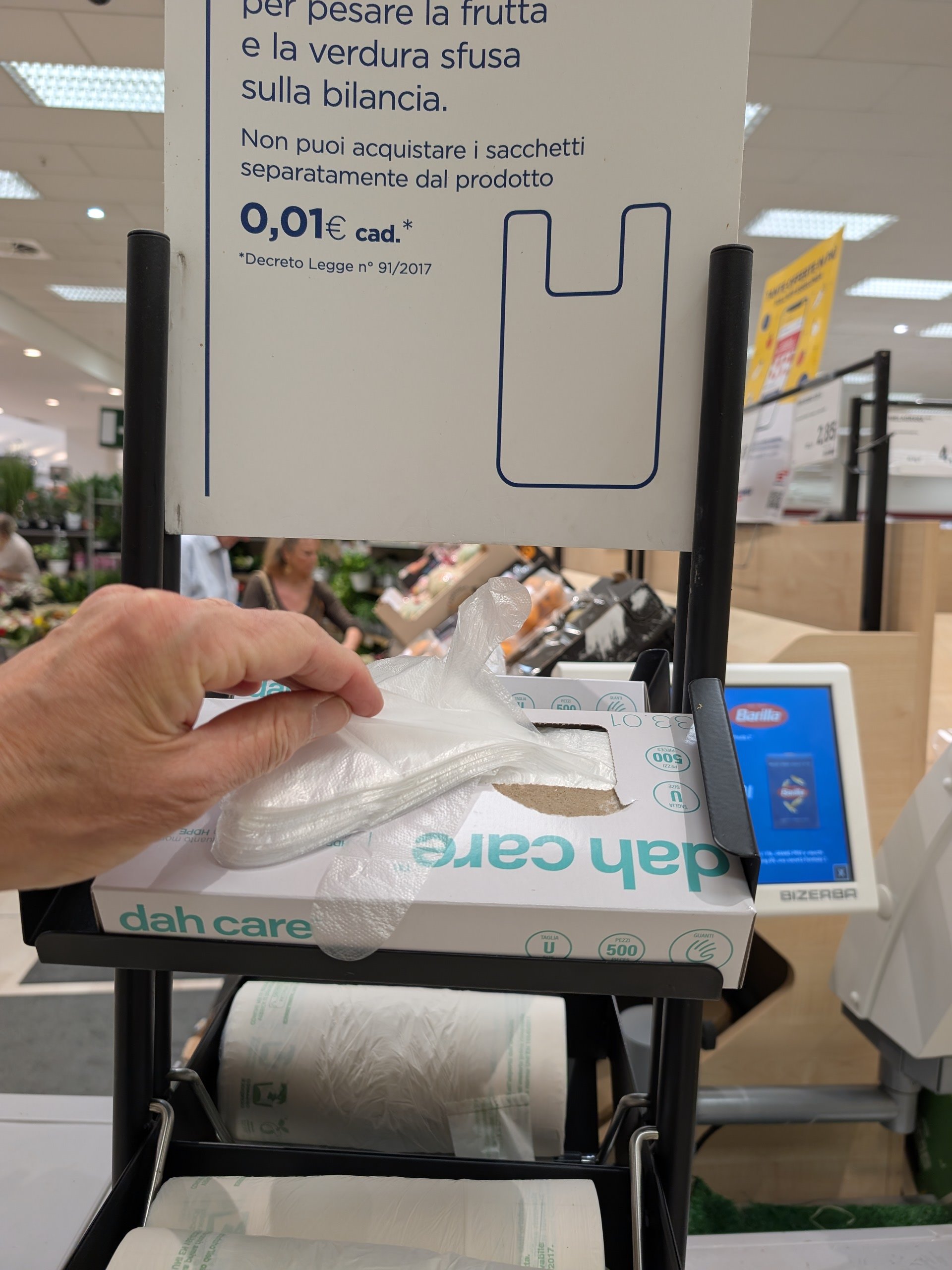 A shopper getting a plastic glove to select fuit from an Italian supermarket