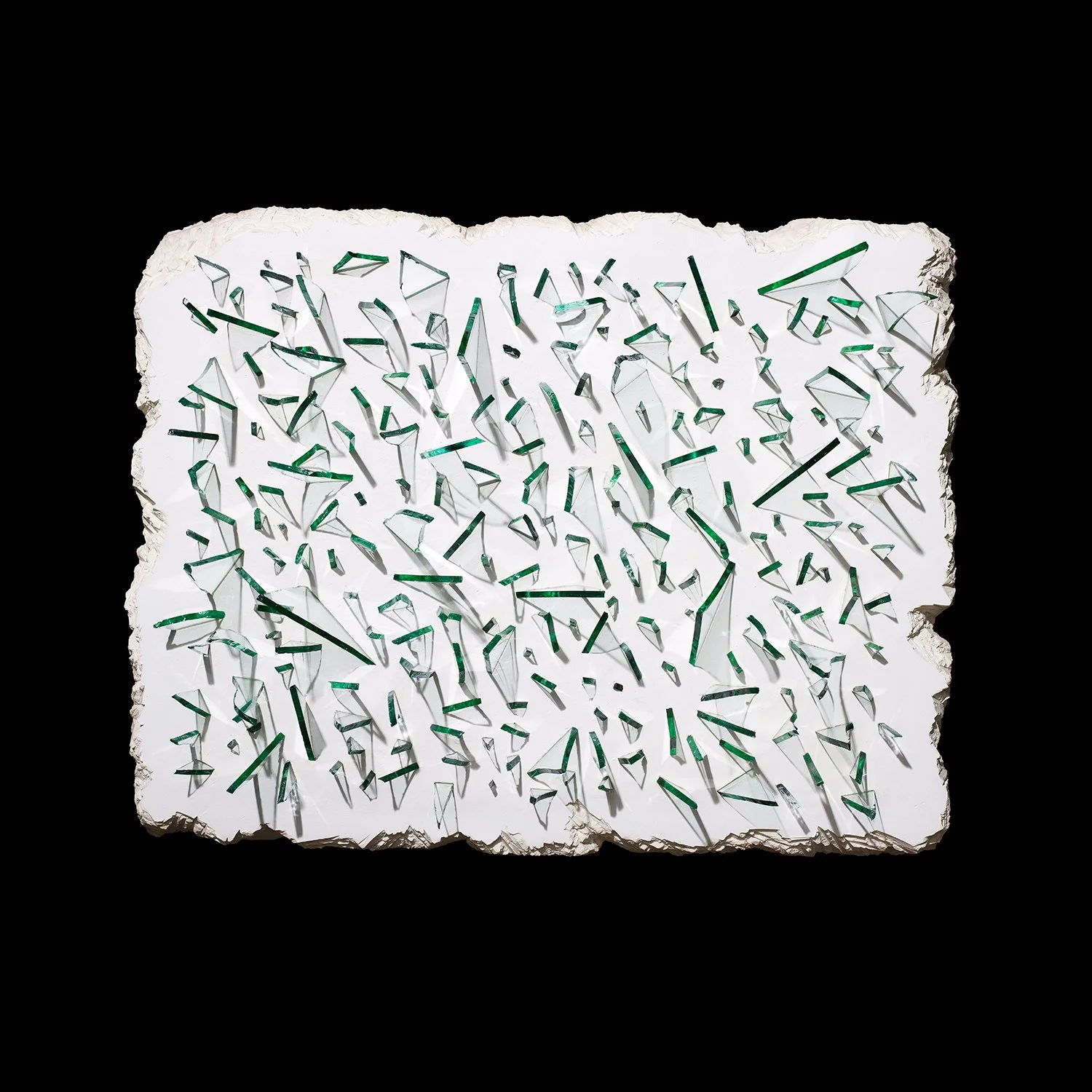 An art installation made of a large white stone slab with jagged edges, embedded with numerous small, irregularly shaped pieces of broken glass reflected against a black background.