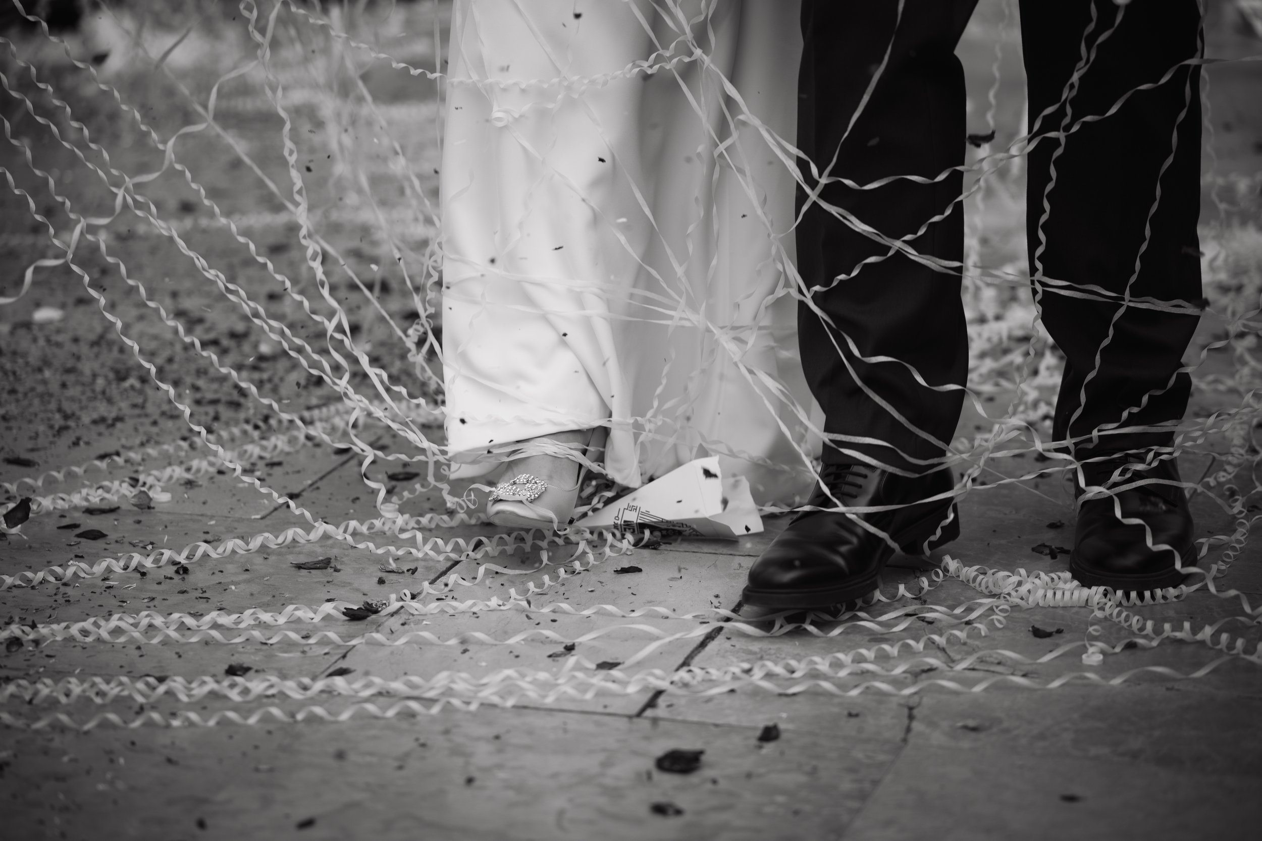 Una persona con vestido de boda y en movimiento, rodeada de serpentinas y papel picado en una celebración al aire libre.