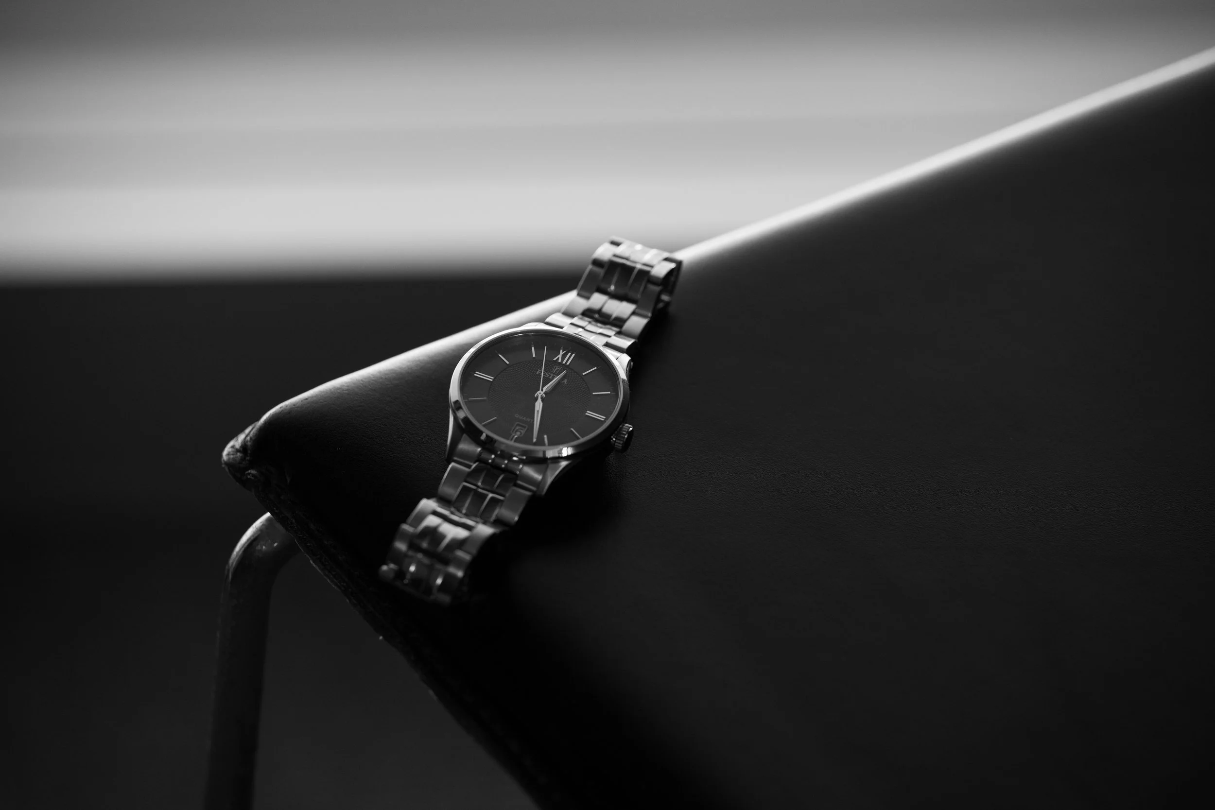 Reloj de pulsera de metal en una superficie negra con fondo gris.