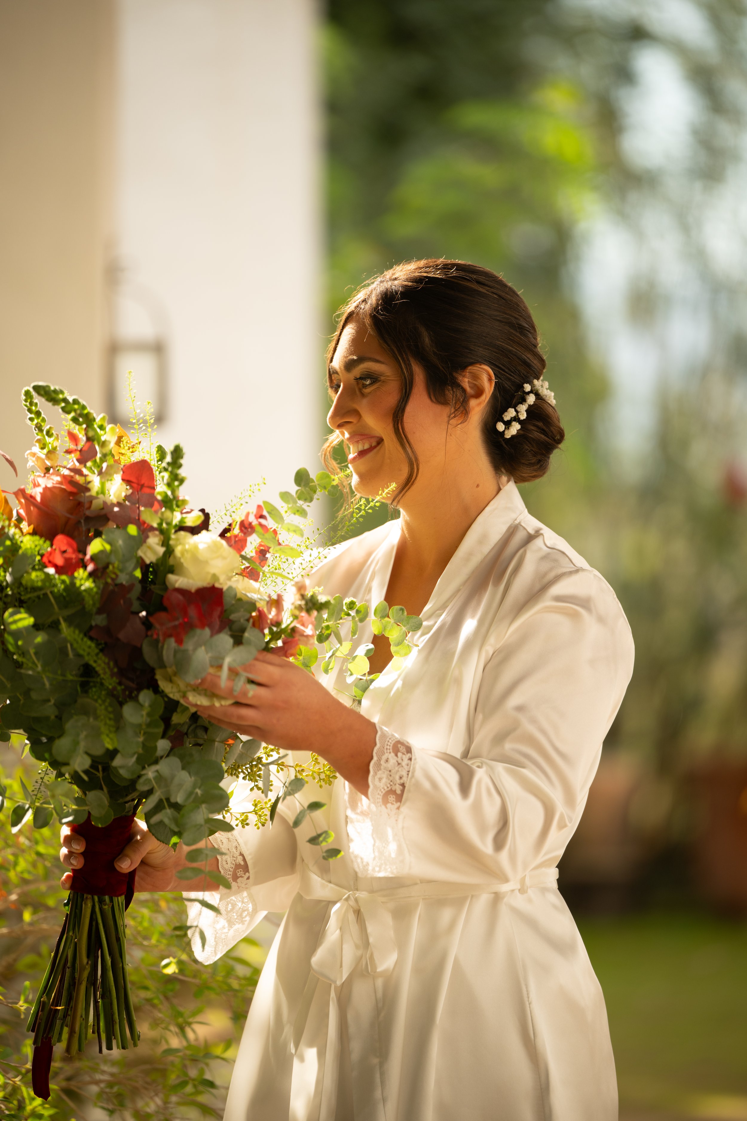 Mujer con vestido blanco sosteniendo un ramo de flores en un ambiente natural