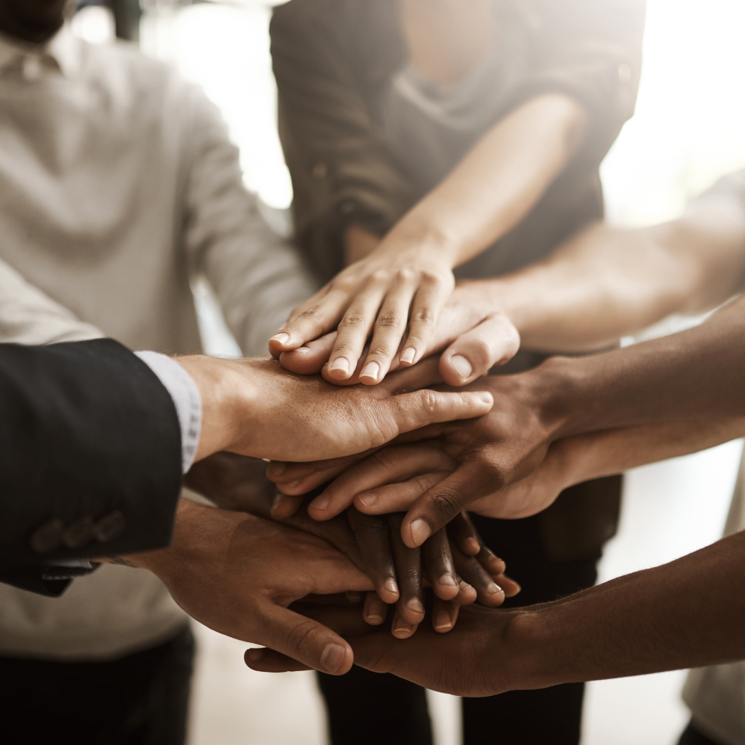 Multiple diverse hands stacked together in a show of unity and teamwork.