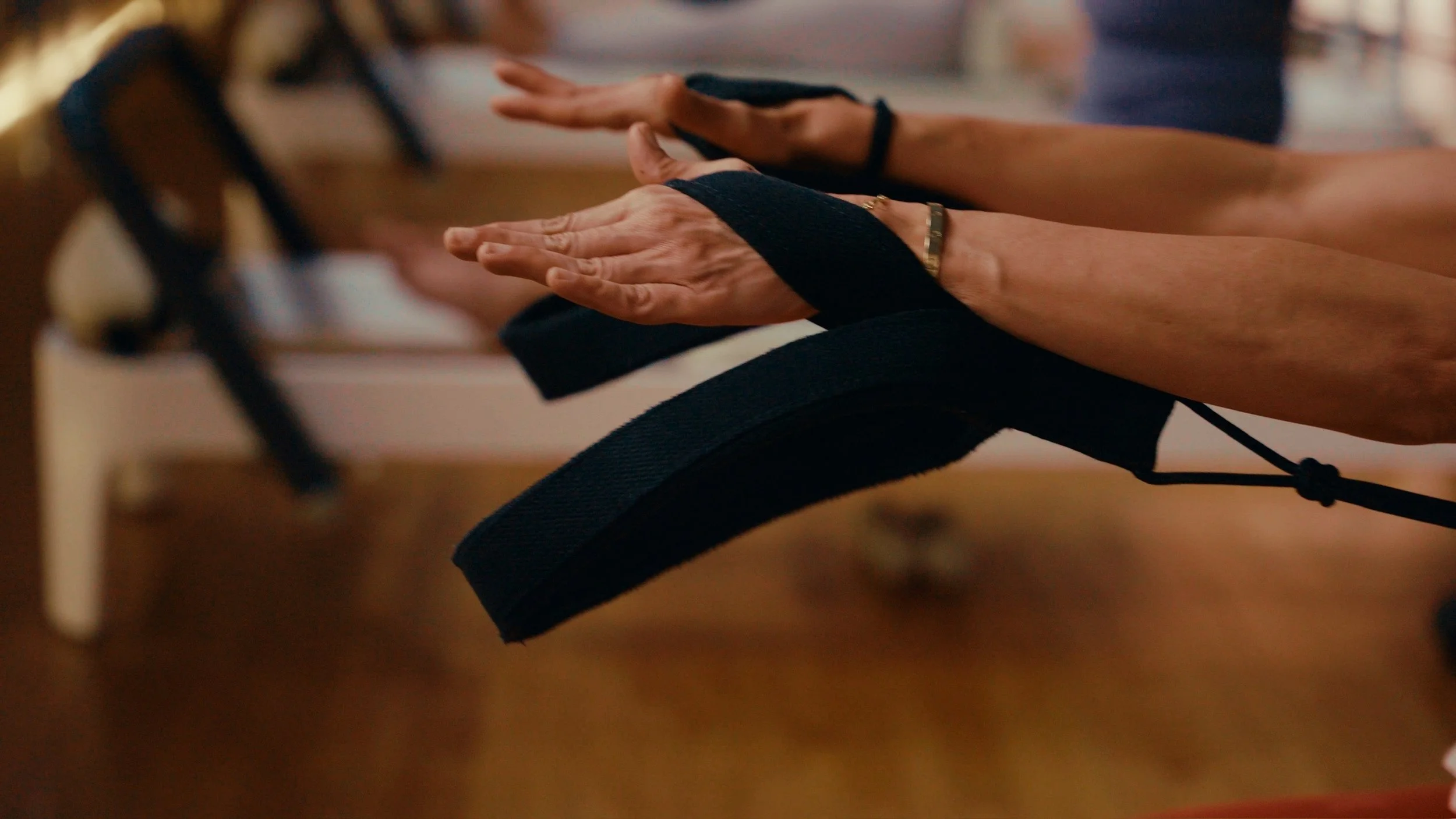 Close-up of a person's hands resting on a black backpack, with a blurred background.