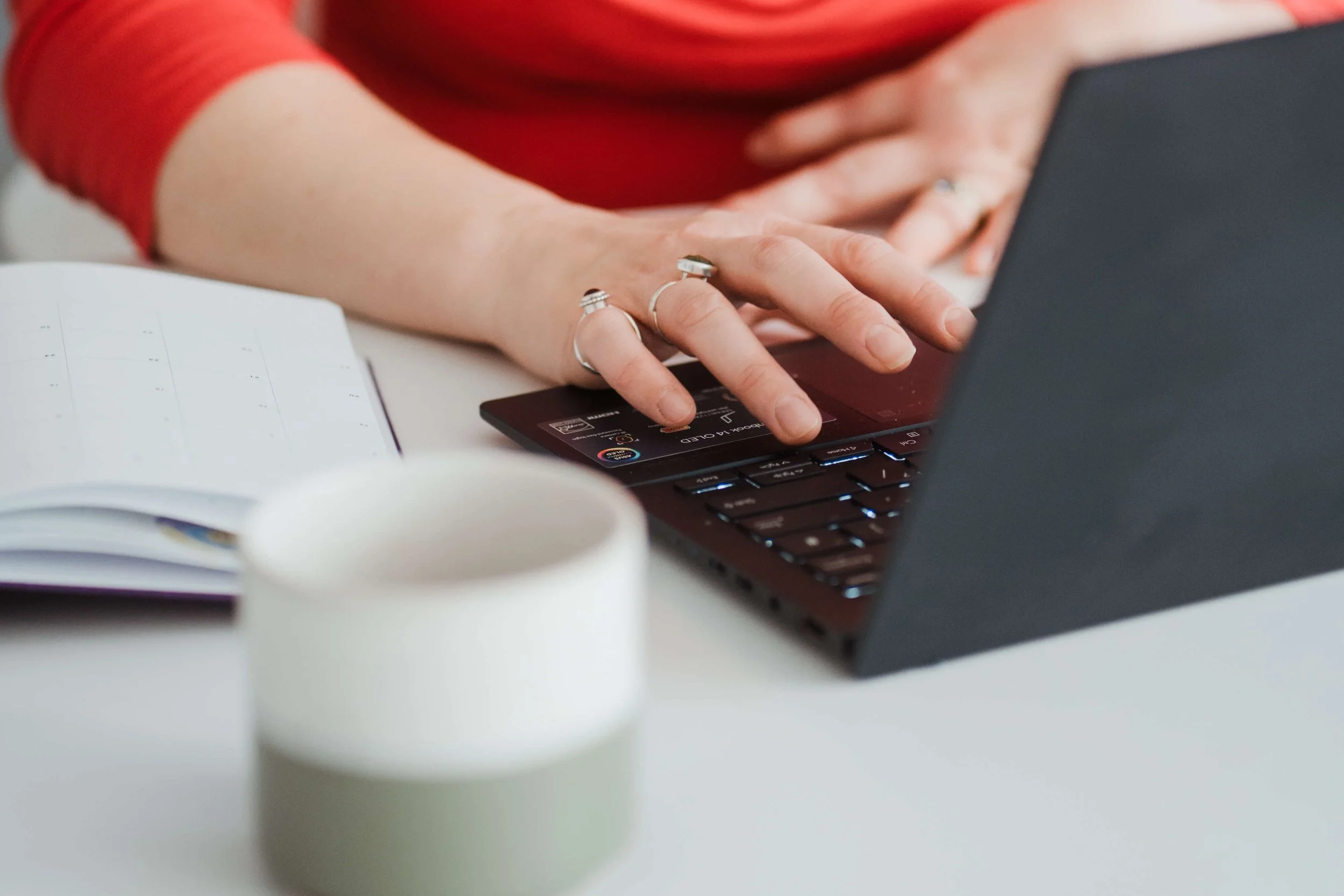 A hand at a laptop typing up access and inclusion consultancy notes.