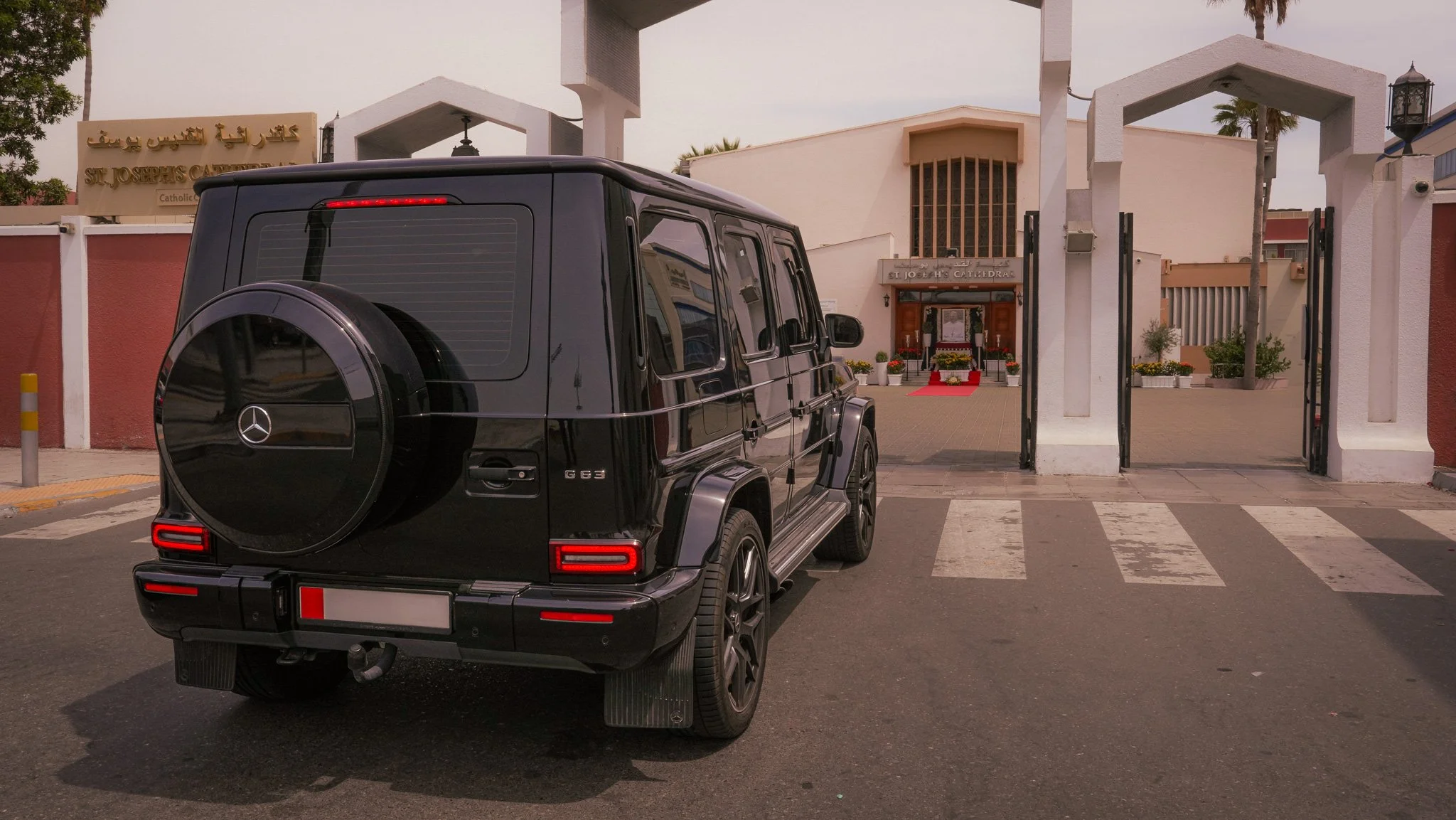 Black Mercedes-Benz G-Class SUV parked in front of the St. Joseph's Cathedral entrance with a red carpet and floral arrangements.