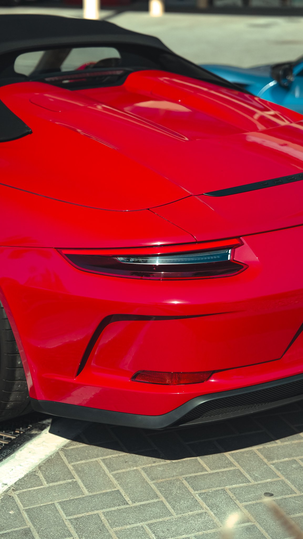 Close-up of the front of a red sports car with sleek headlights and aerodynamic design, parked on a paved surface.