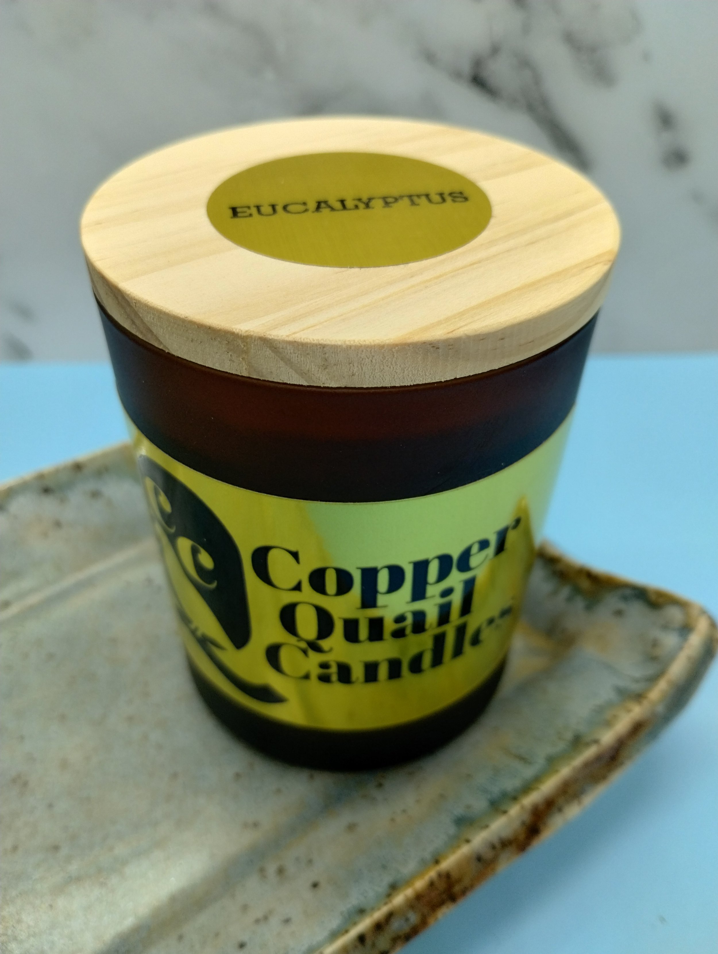 candle in a frosted brown jar with a wood lid
