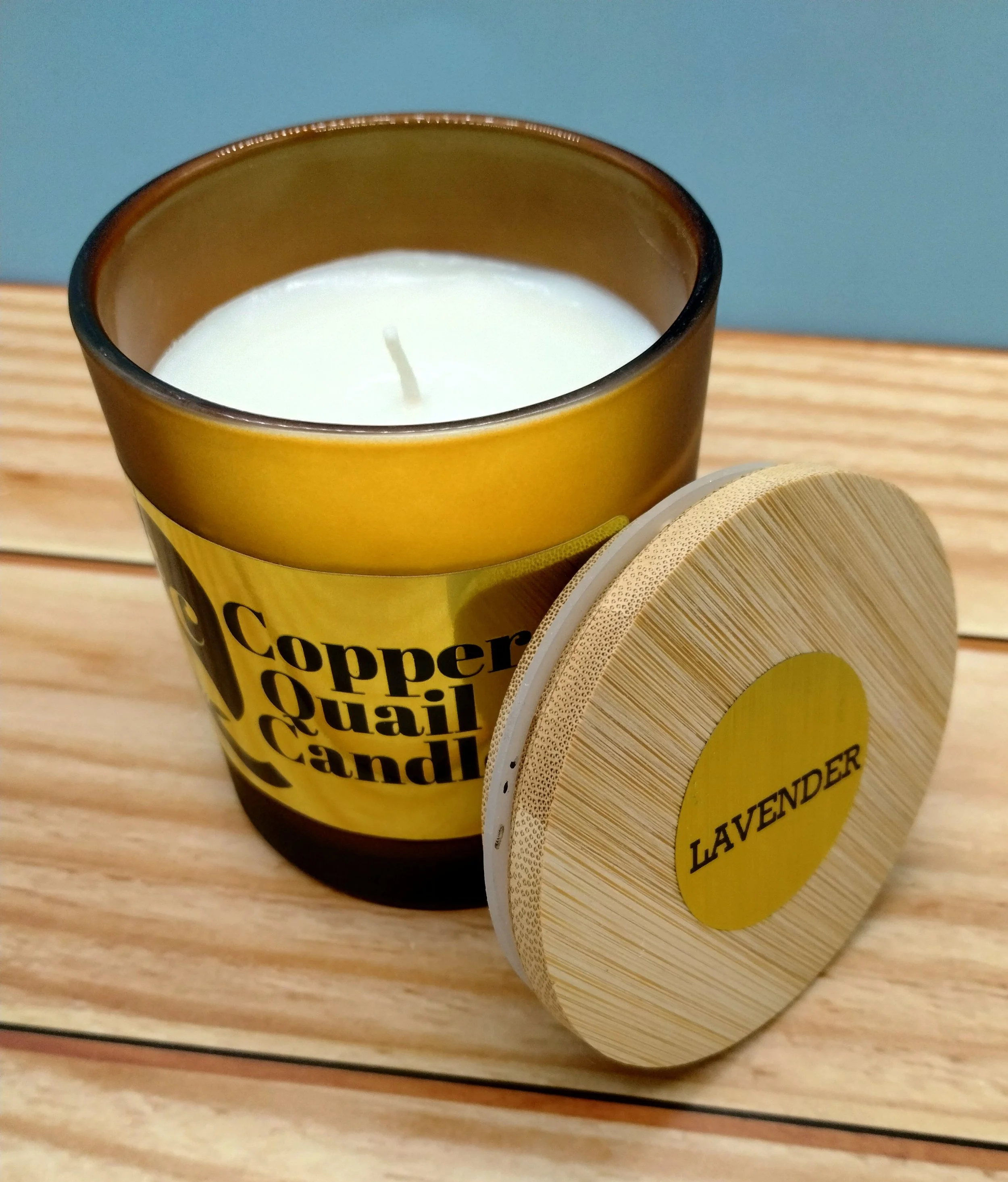 candle in a frosted brown jar with a wood lid next to it