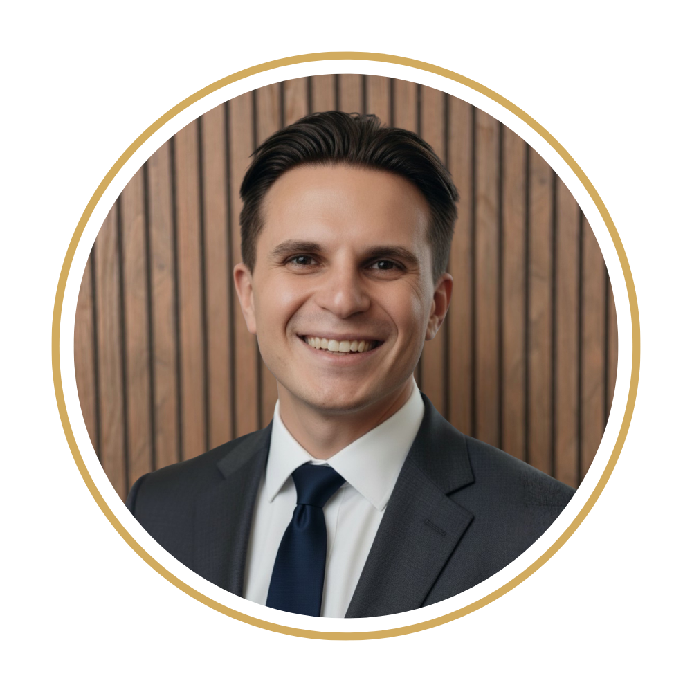 Matthew in a suit smiling in front of a wooden background.