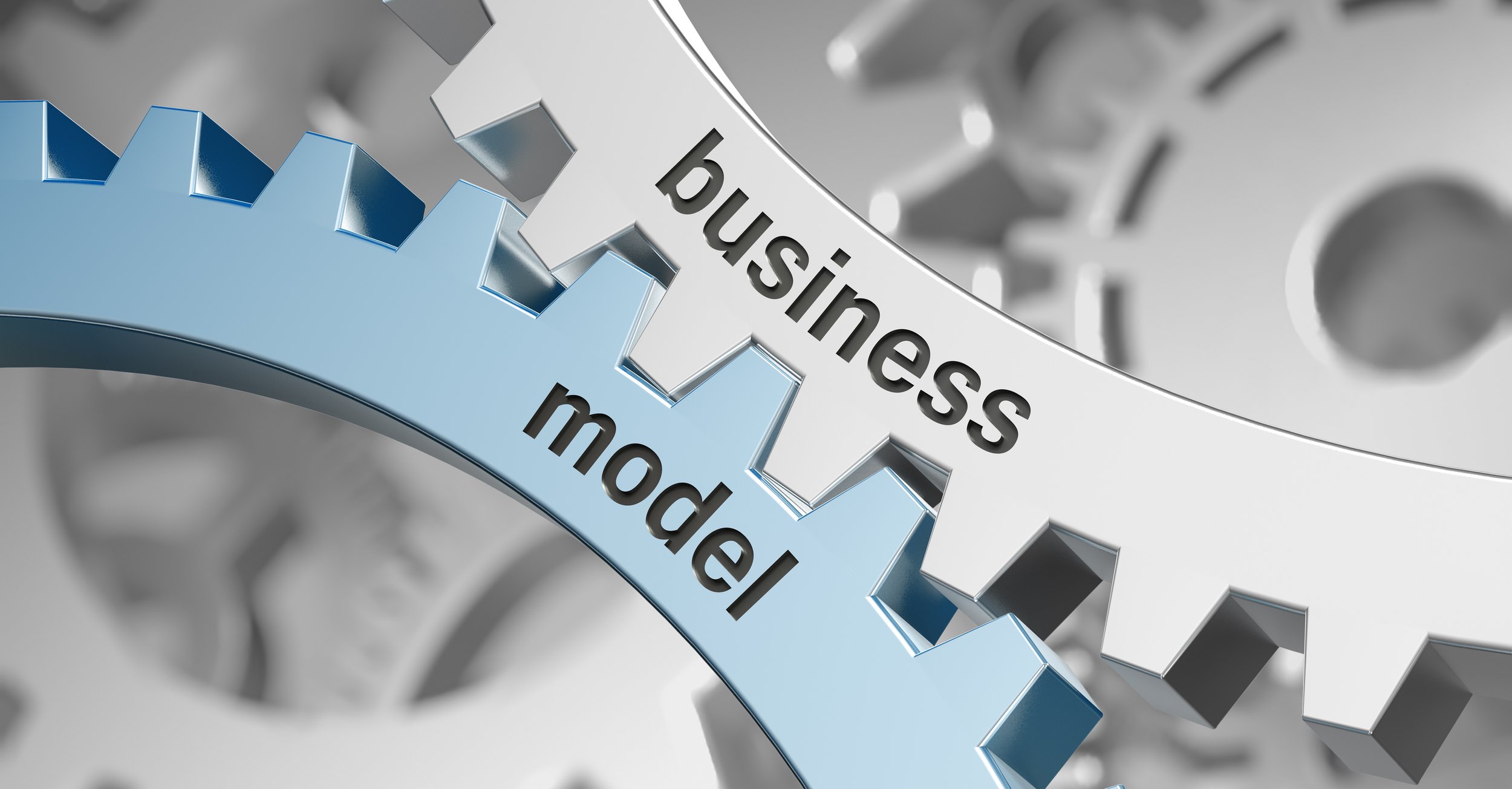 Close-up of interlocking metallic gears with the words 'business', 'model', and 'what' engraved on two of them.