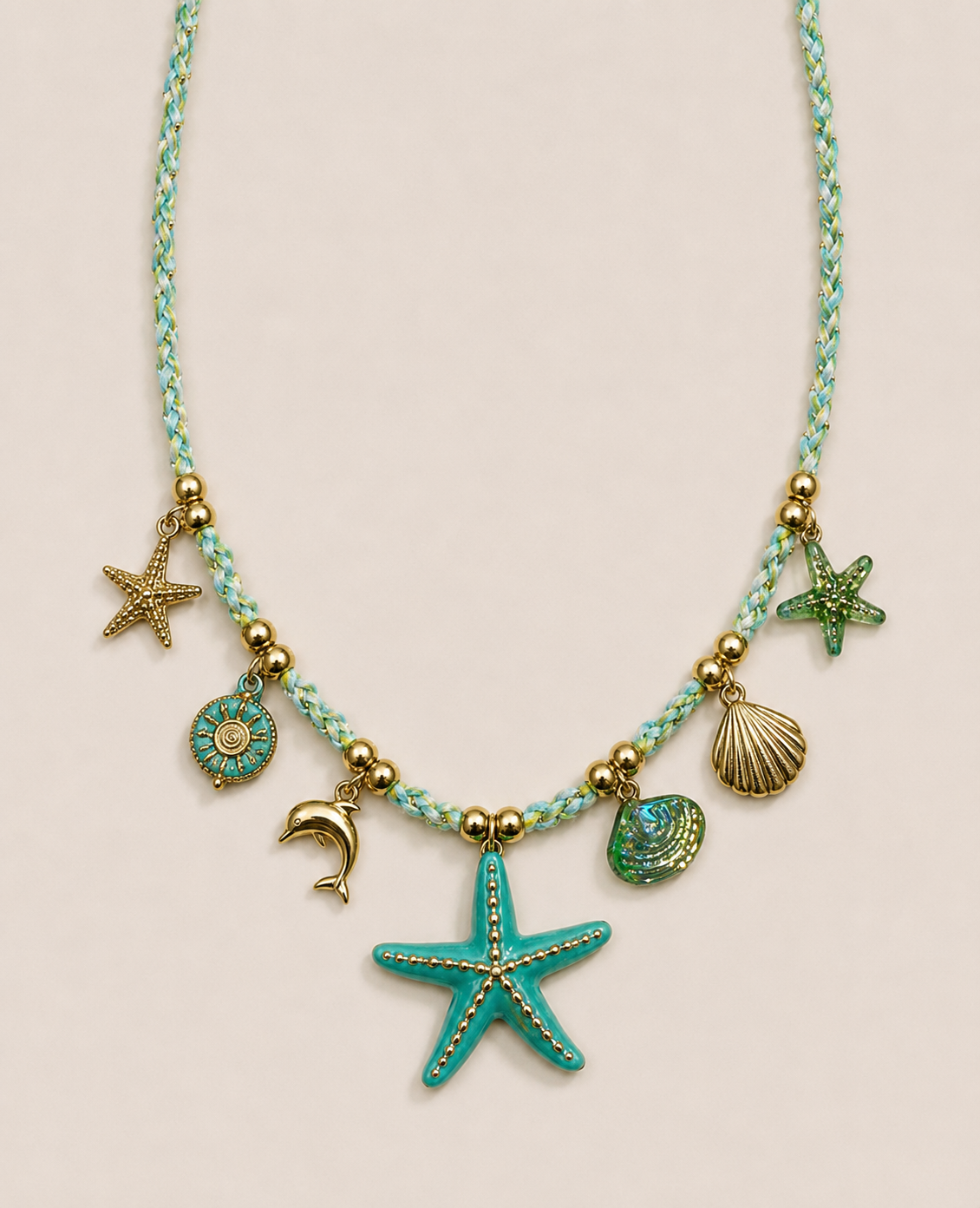 Collier de plage avec pendentifs en forme d'étoiles de mer, coquillage, dauphin, sun, et perle, avec un fil tressé bleu et or.