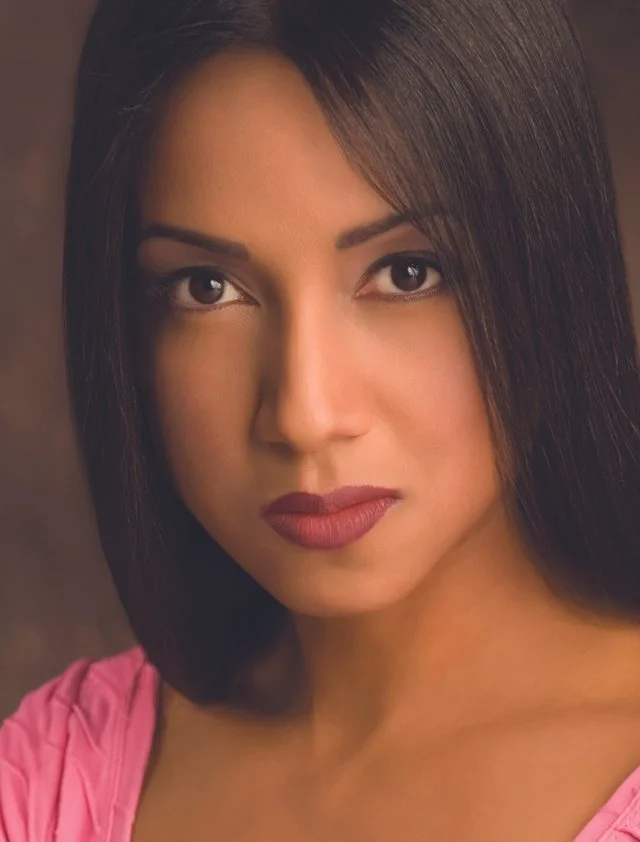 Close-up portrait of a woman with straight dark hair, expressive eyes, and wearing pink clothing. Dr. Jimenez. Dr. Carmen Jimenez