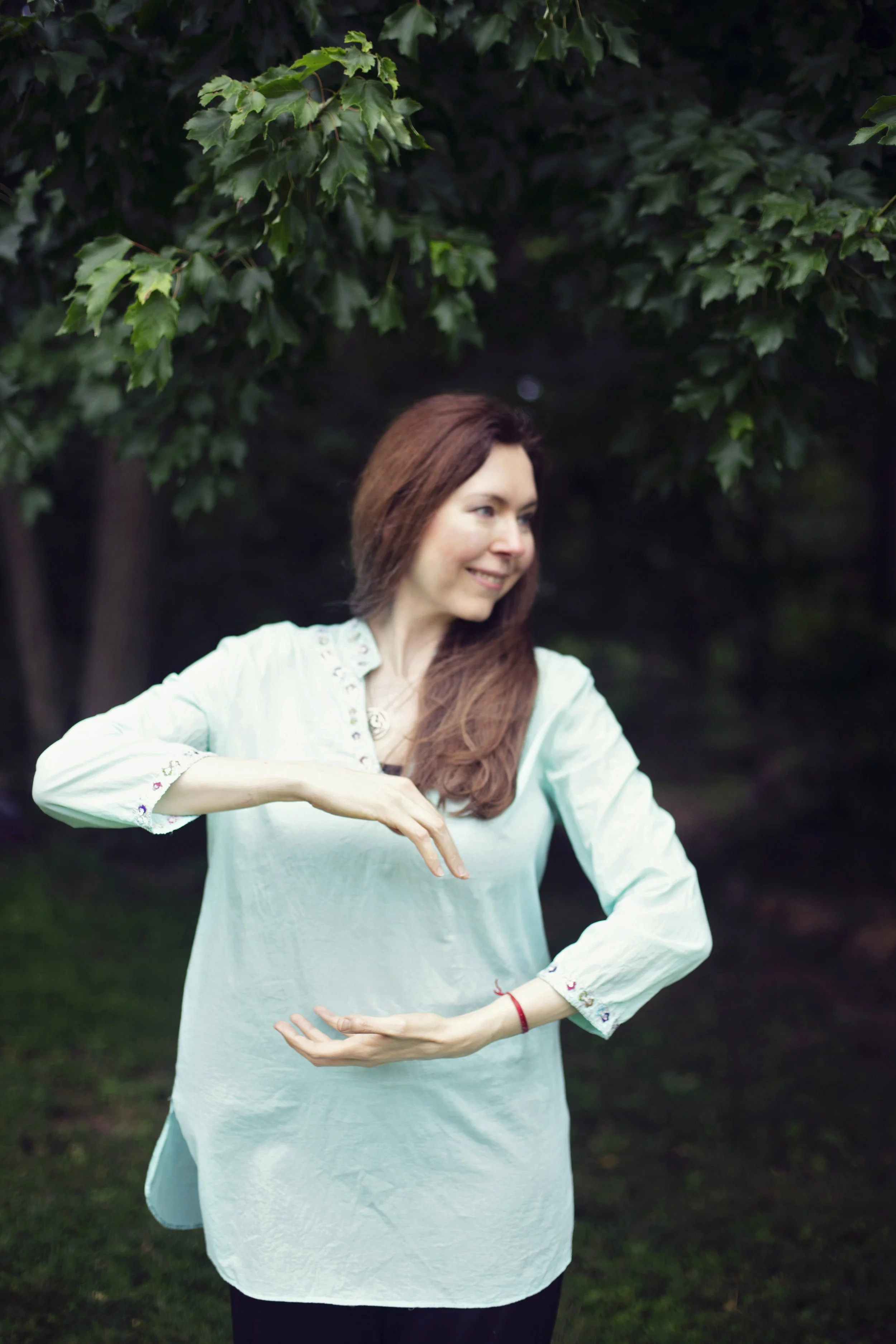 Dr. Lienna Wilson practicing Tai Chi outdoors, arms extended in a slow, structured movement