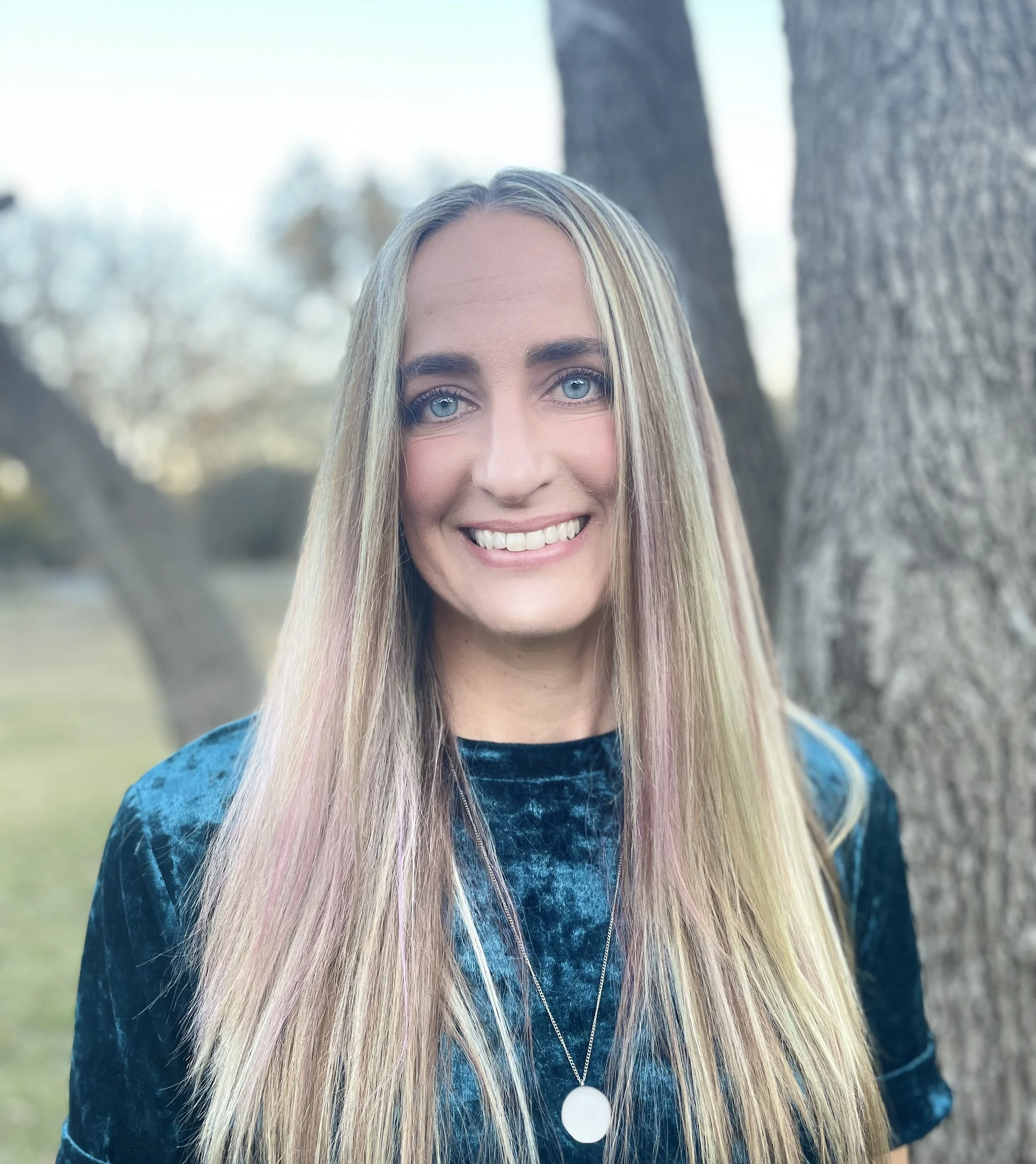 Dr. Sam Scarnato, PsyD, a pediatric functional nutrition and mental health practitioner and founder of Belief in Joy, smiling outdoors beside a tree in a deep teal top