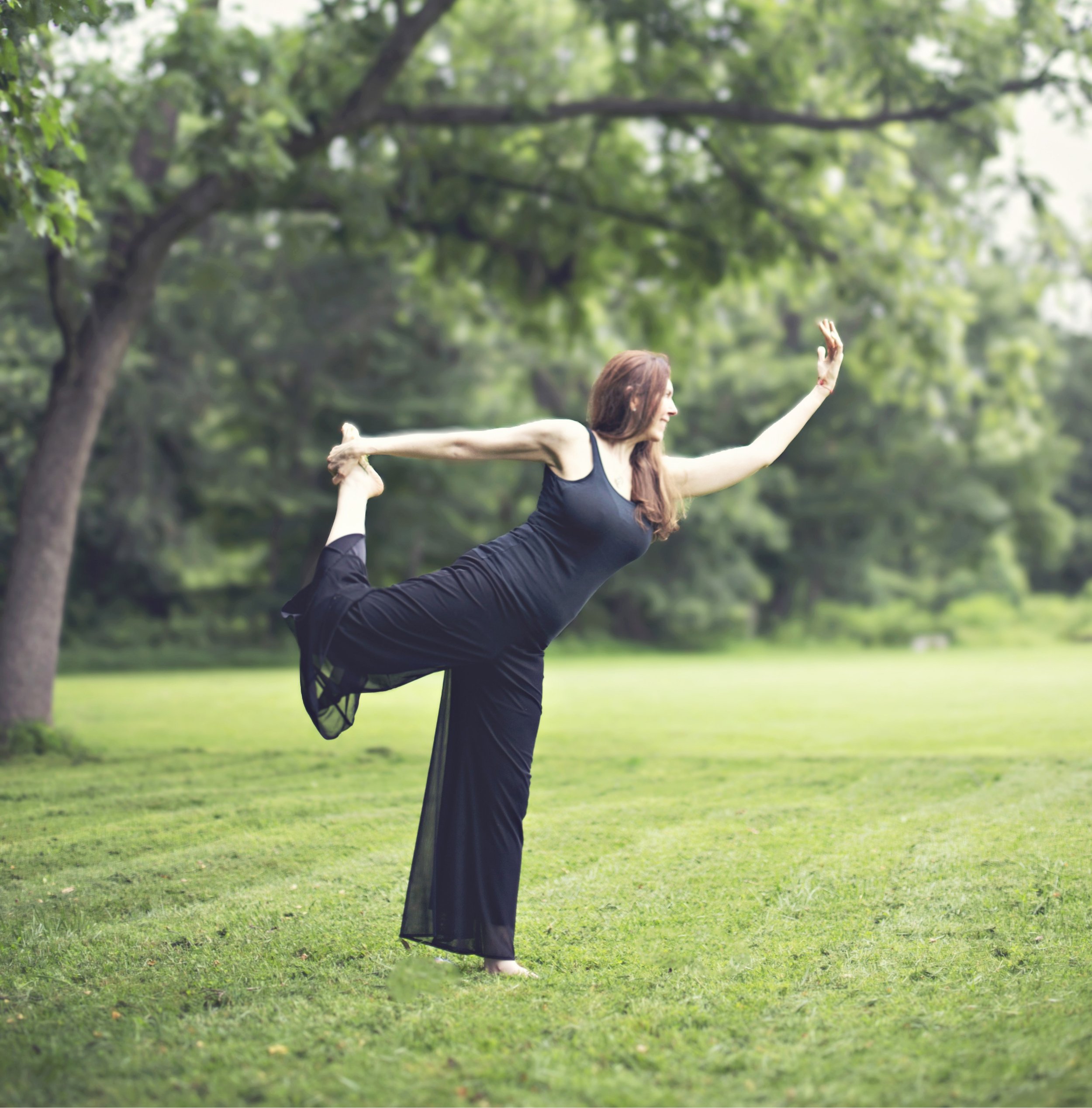 woman in a standing yoga pose on grass