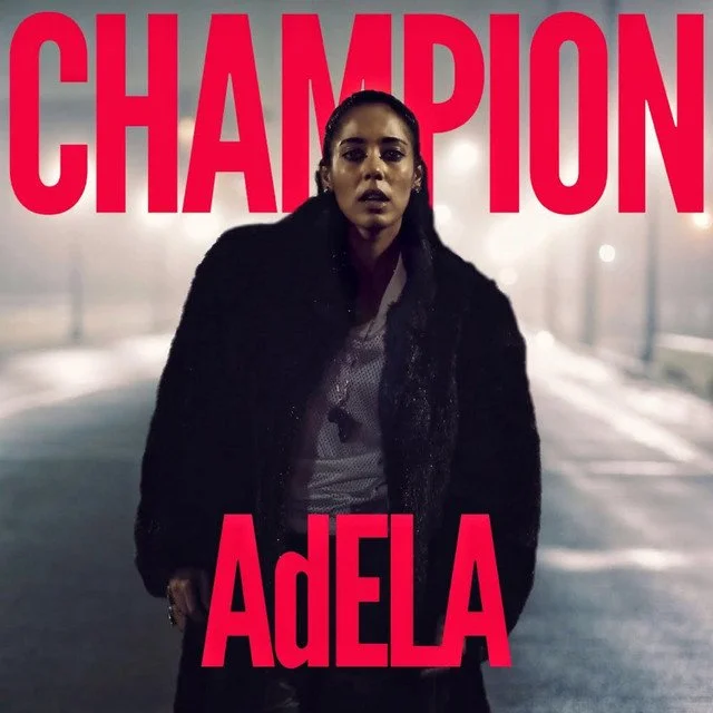 A woman with dark hair in pigtails standing on a foggy street at night, with the words "CHAMPION" and "ADELA" in large red letters over her.