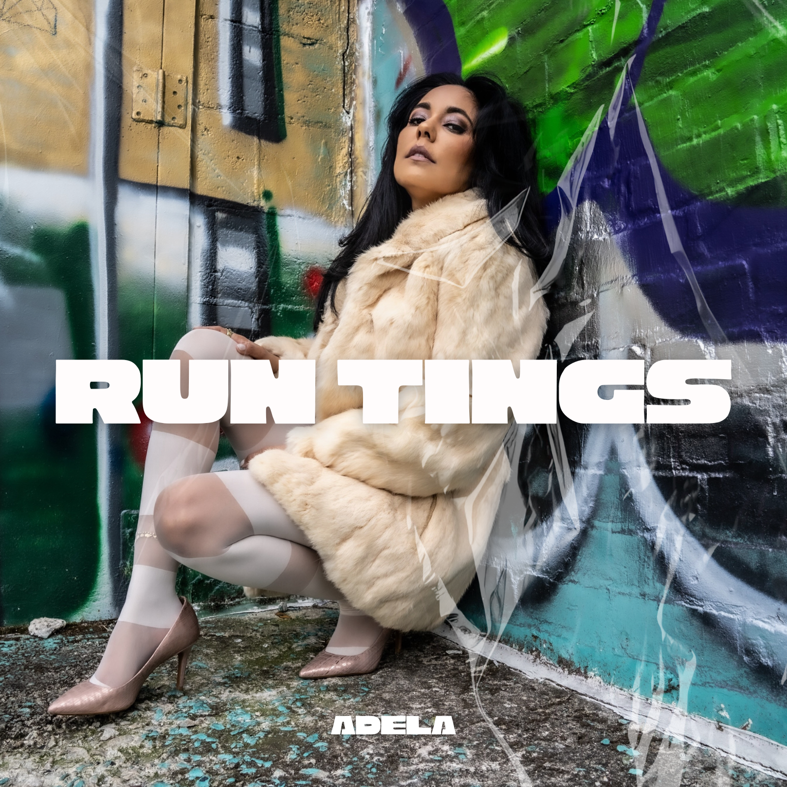 A woman with long dark hair, wearing a beige fur coat and sheer white stockings, sitting against a colorful graffiti-covered wall. She has a confident expression and is holding a smartphone. There is bold white text that says "RUN THINGS" across the 