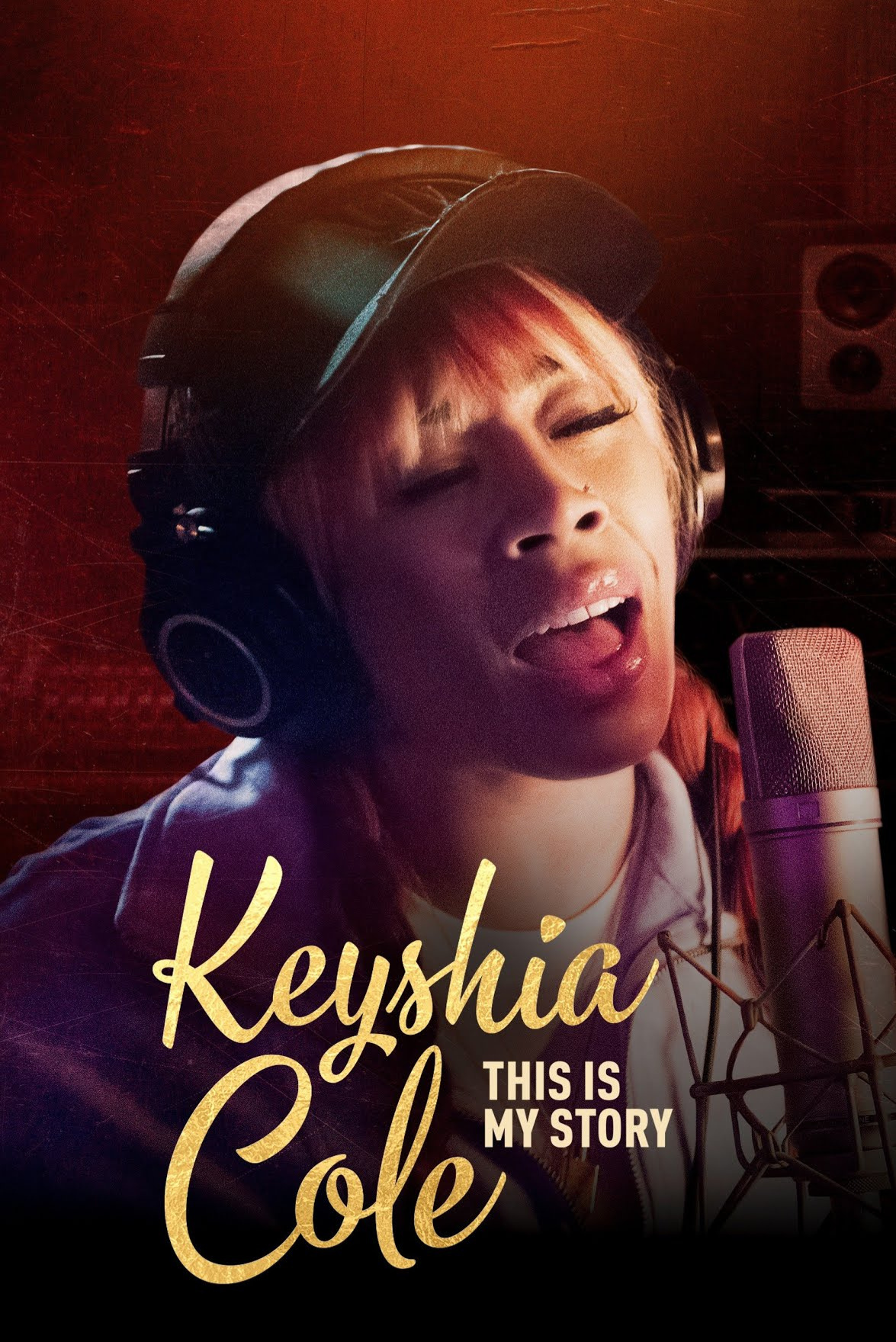 A woman wearing a black helmet, singing into a microphone in a recording studio with red lighting. The text on the image reads "Keyshia Cole: This is My Story."