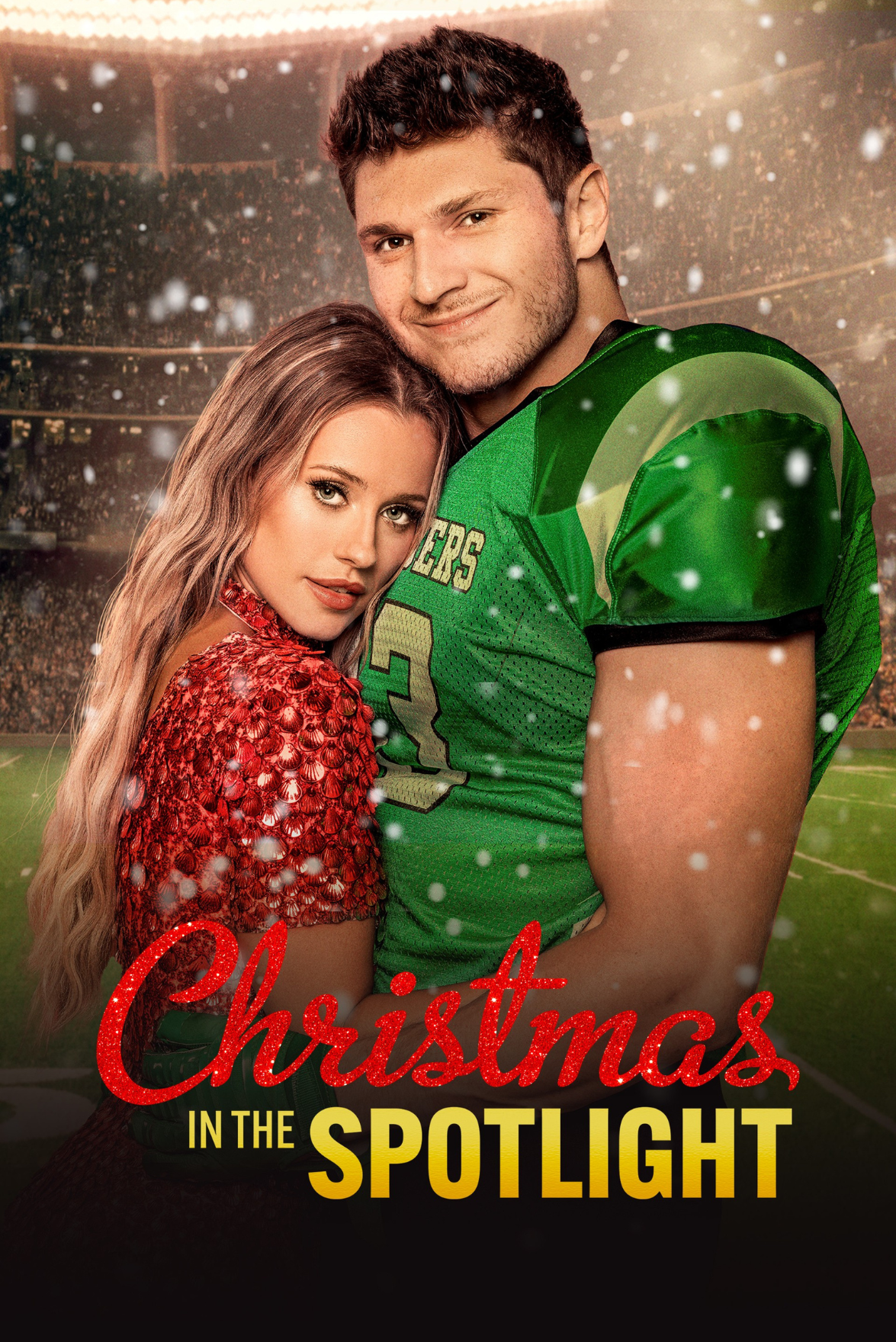A young woman with long wavy blonde hair and a young man in a green football jersey standing close together on a football field, with a stadium in the background, snow falling, and red Christmas text overlay reading 'Christmas in the Spotlight'.