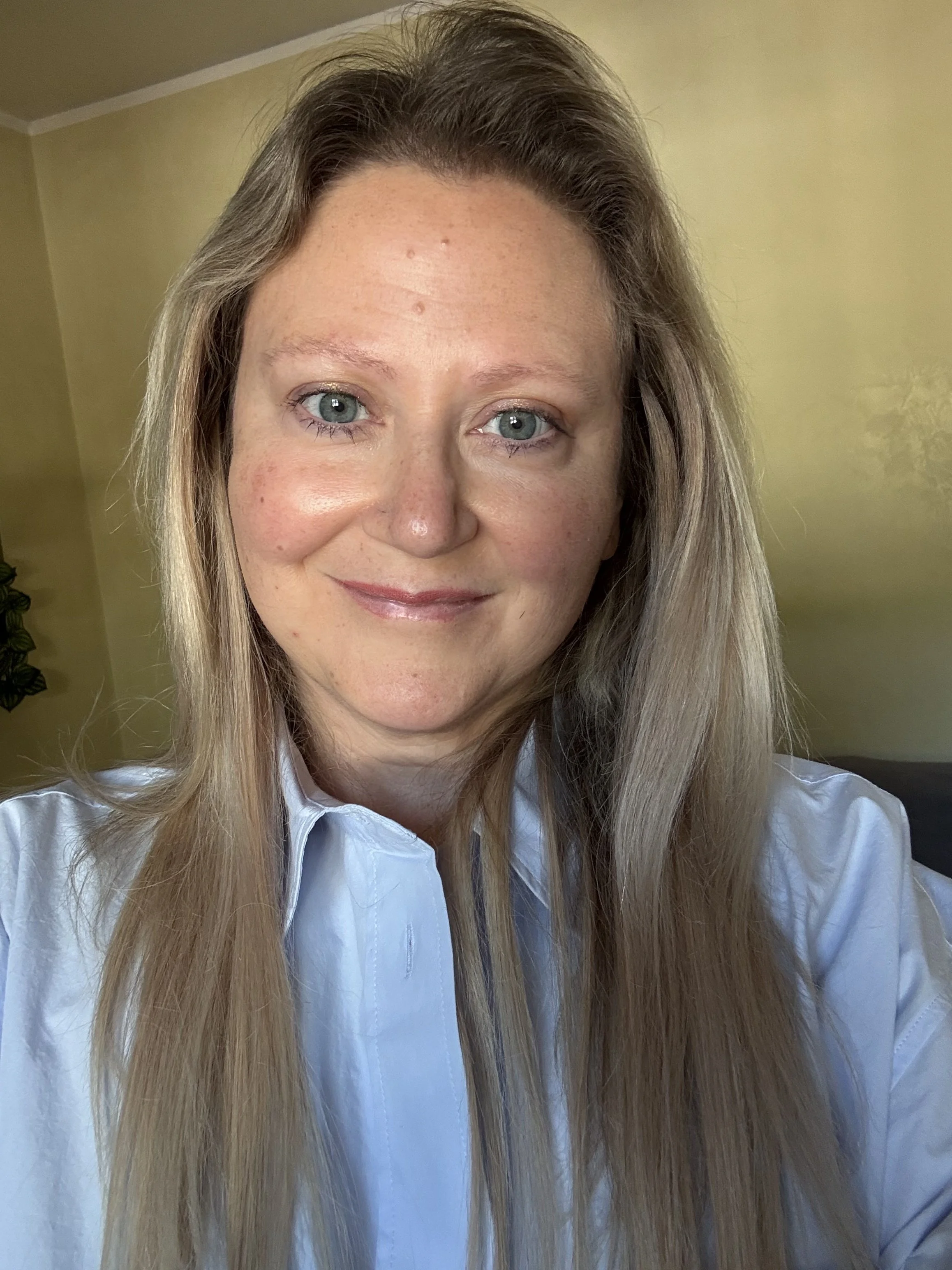 Woman with blonde hair and blue eyes wearing a blue shirt