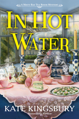Book cover titled 'In Hot Water' by Kate Kingsbury, featuring a tea room scene with a pink tablecloth, teapots, cups, and saucers, against a window background showing a garden.