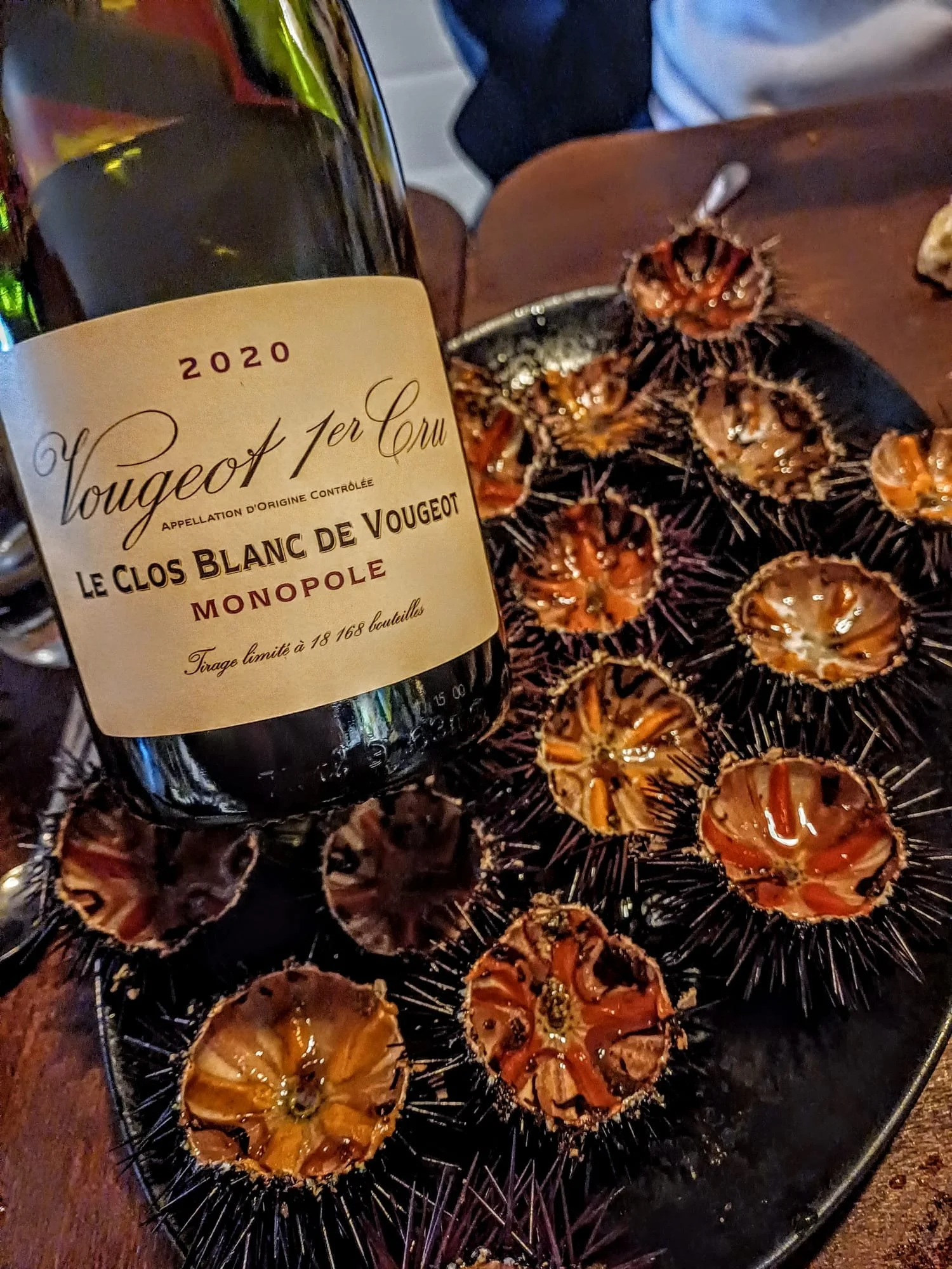 Bouteille de vin blanc 'Voug¸ot premier Cru' 2020 et coquillages grillés sur un plateau en corde de jute