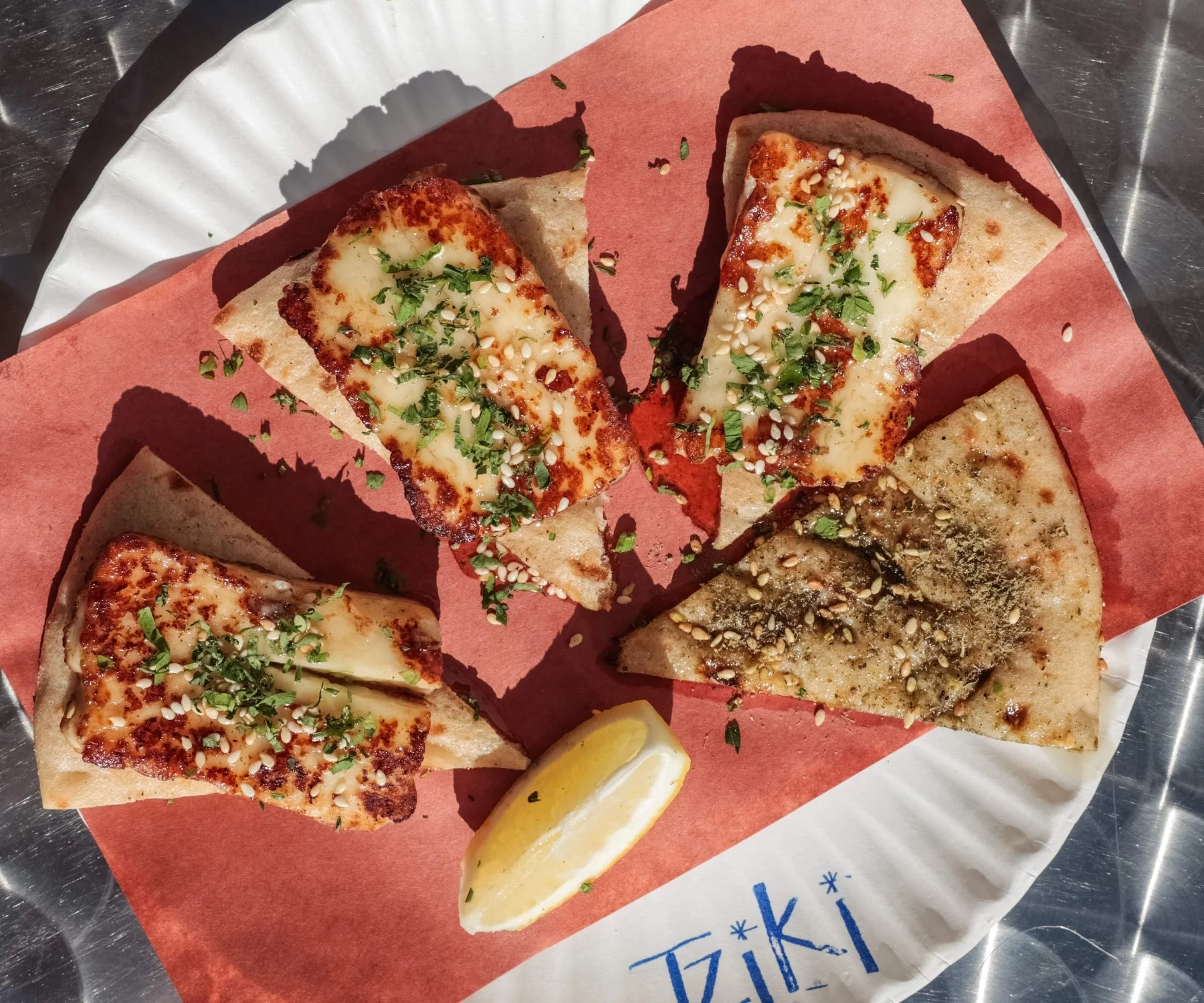 Grilled PDO halloumi Cypriot cheese on handmade pita with sesame, oregano, and lemon at Tziki, authentic Greek souvlaki shop in Chelsea Manhattan NYC