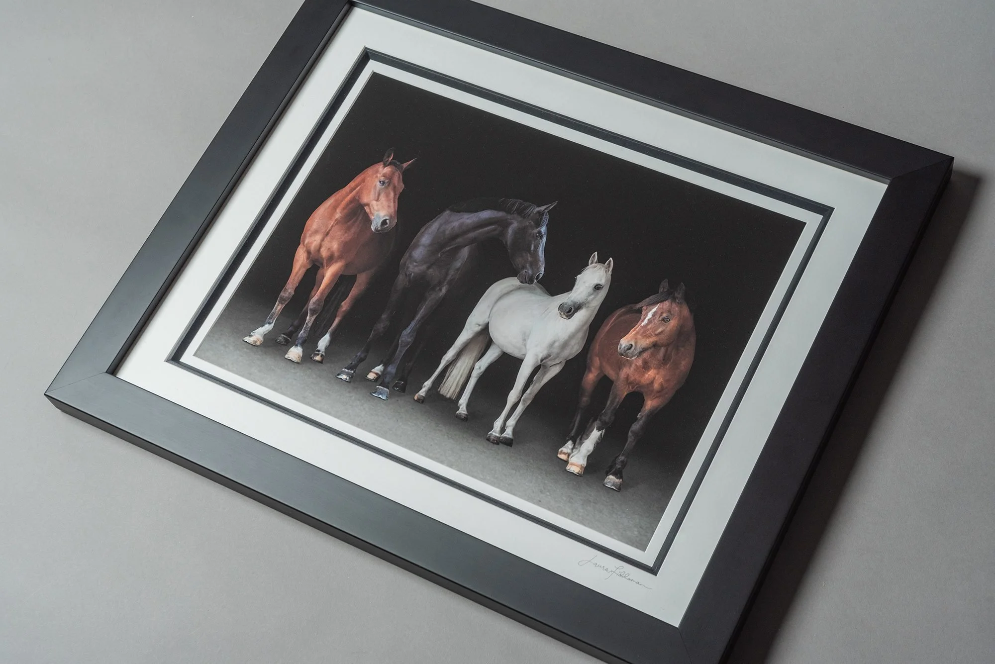 Framed artwork of four horses standing side by side against a dark background.