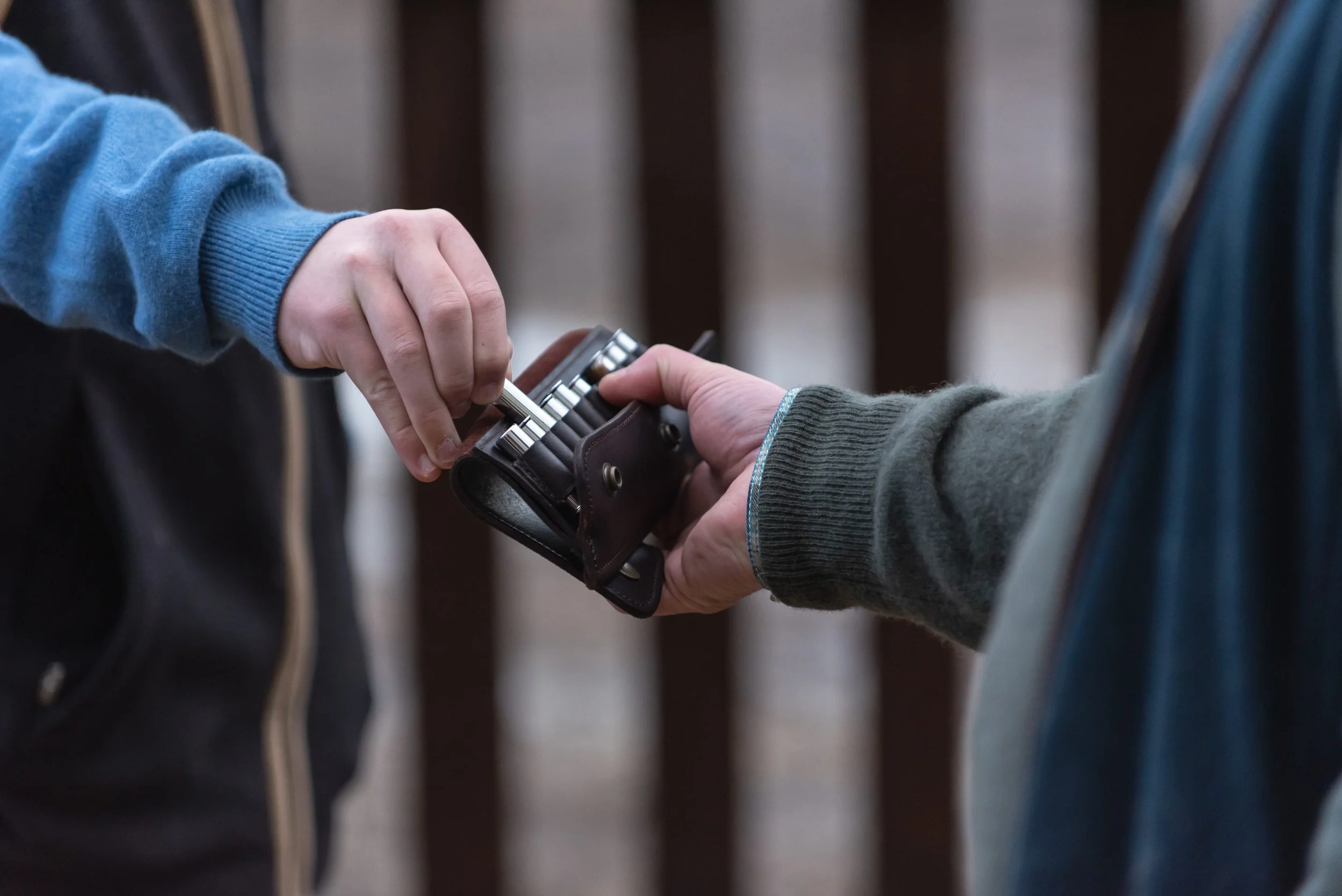 Two people exchanging a set of keys, one person holding a key ring and the other receiving it.
