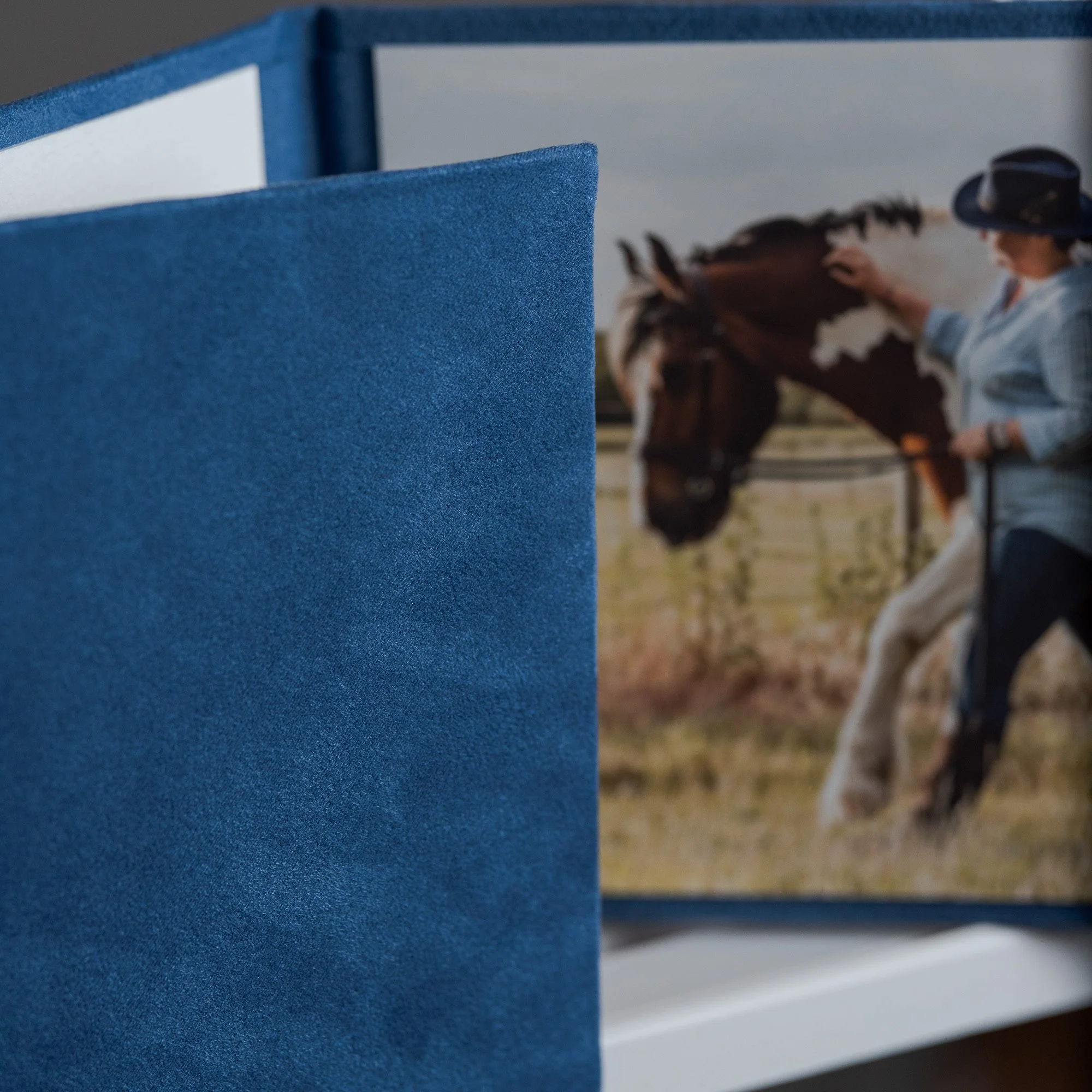 A three fold suede folio in blue depicting Laura and her heart horse Rio in one of the folio photographs.