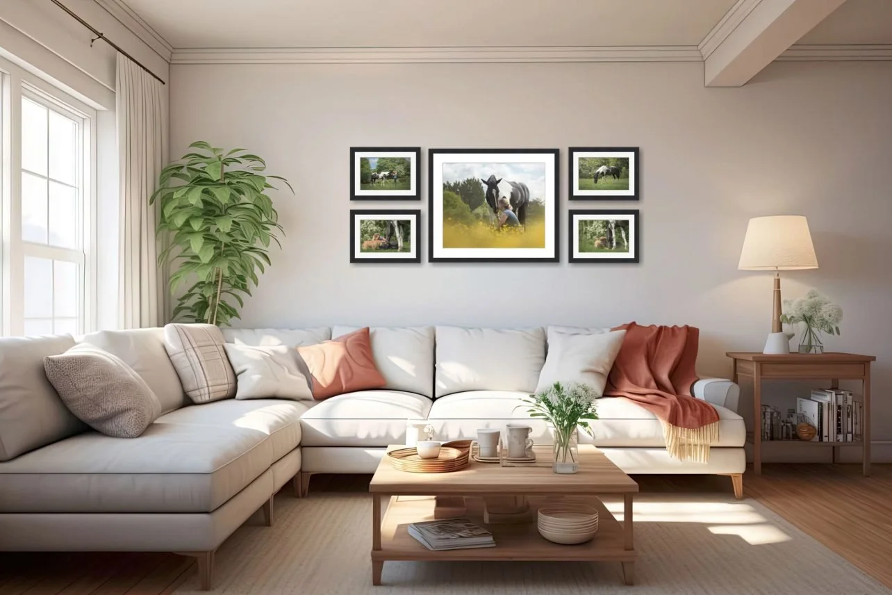 A bright living room with a white sectional sofa decorated with pillows and a throw blanket, a wooden coffee table with coffee mugs and a plant, a bookshelf, a large potted plant, and framed pictures of horses on the wall.