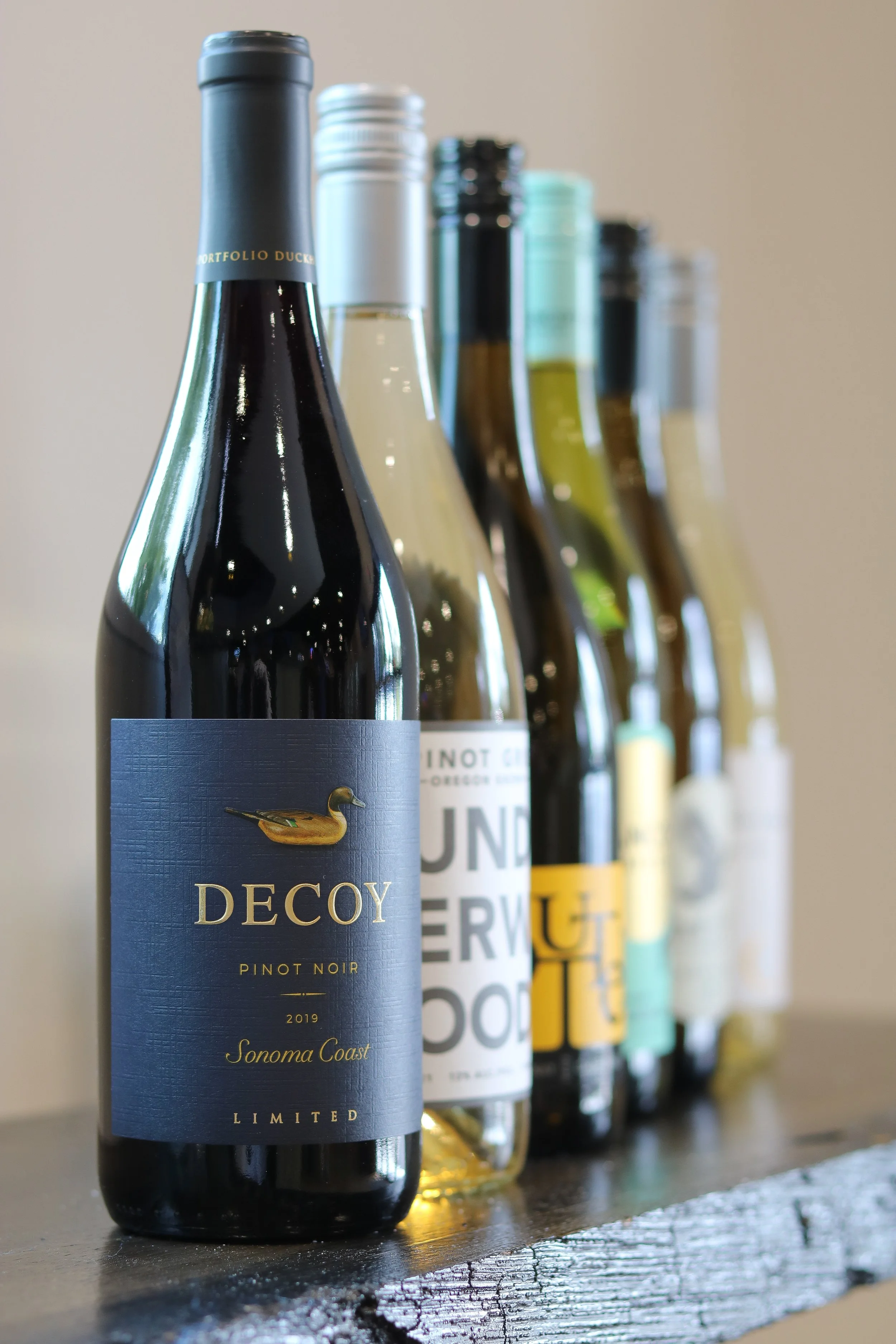 A row of wine bottles on a wooden surface with a blurred background.