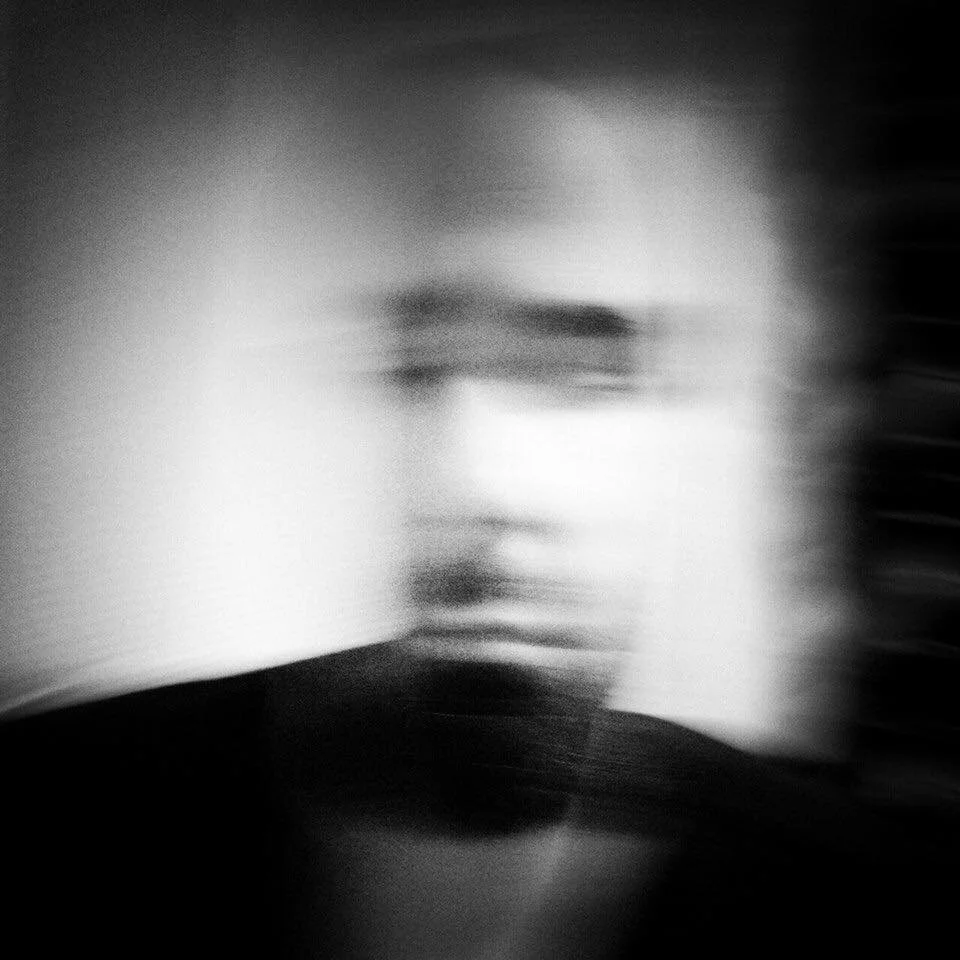 Blurred black and white portrait of a person's face, causing facial features to be indistinct.