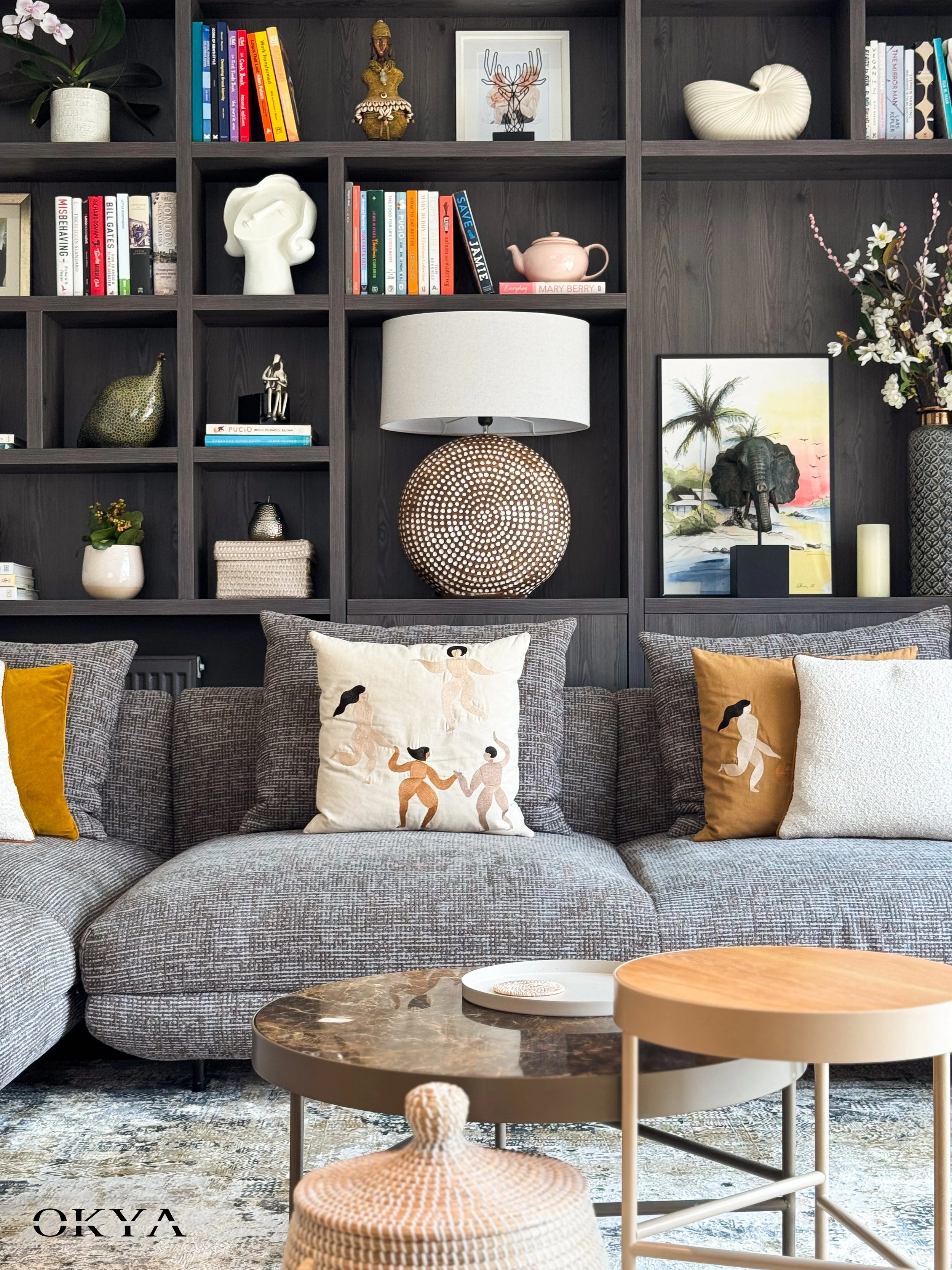 A space that could hold a family during the week and feel genuinely sophisticated at the weekend. Dark stained oak shelving runs the full width of the wall, grounding the room and giving it a depth that pale finishes never could. Chevron oak flooring