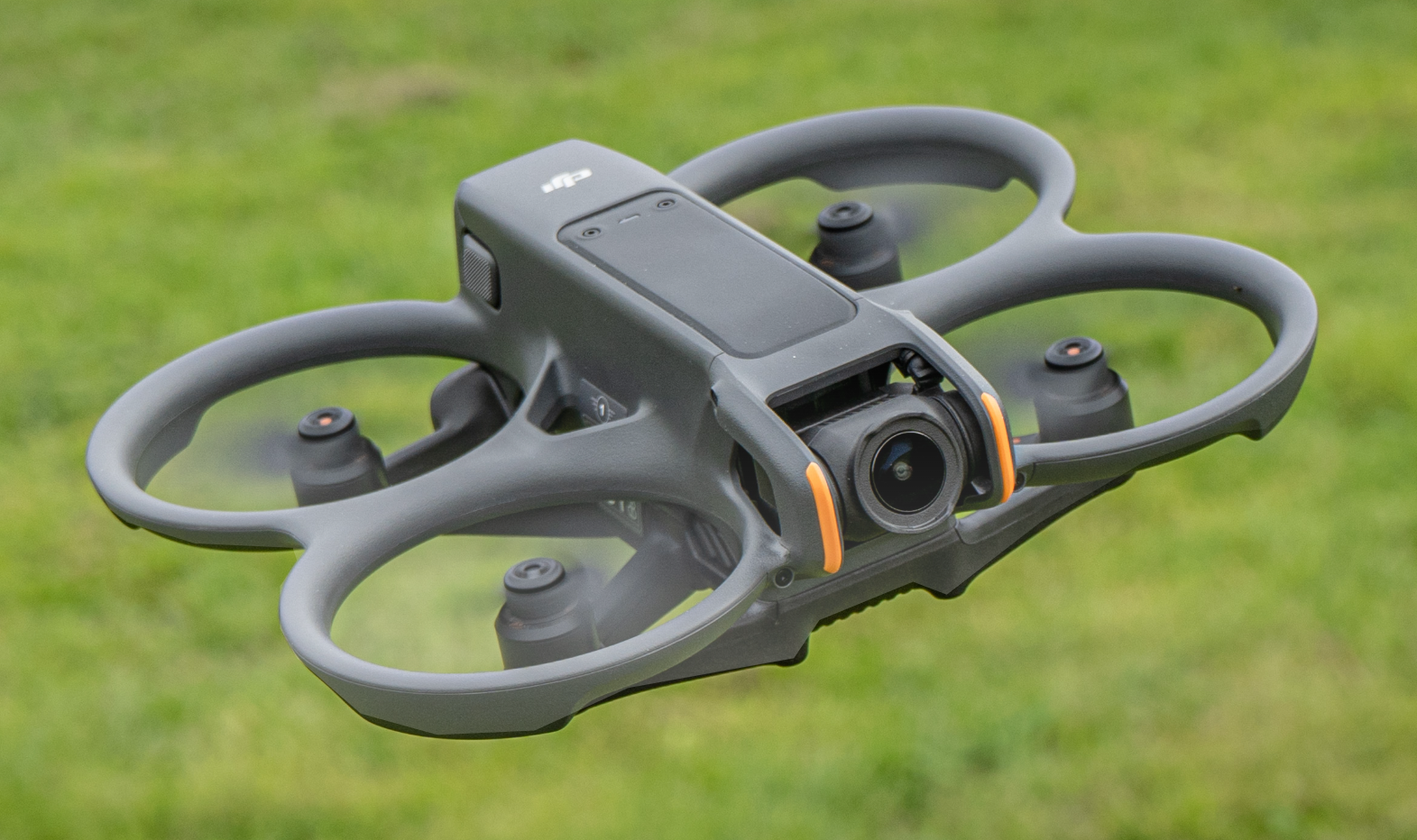 A gray DJI drone with a camera on a grassy field.