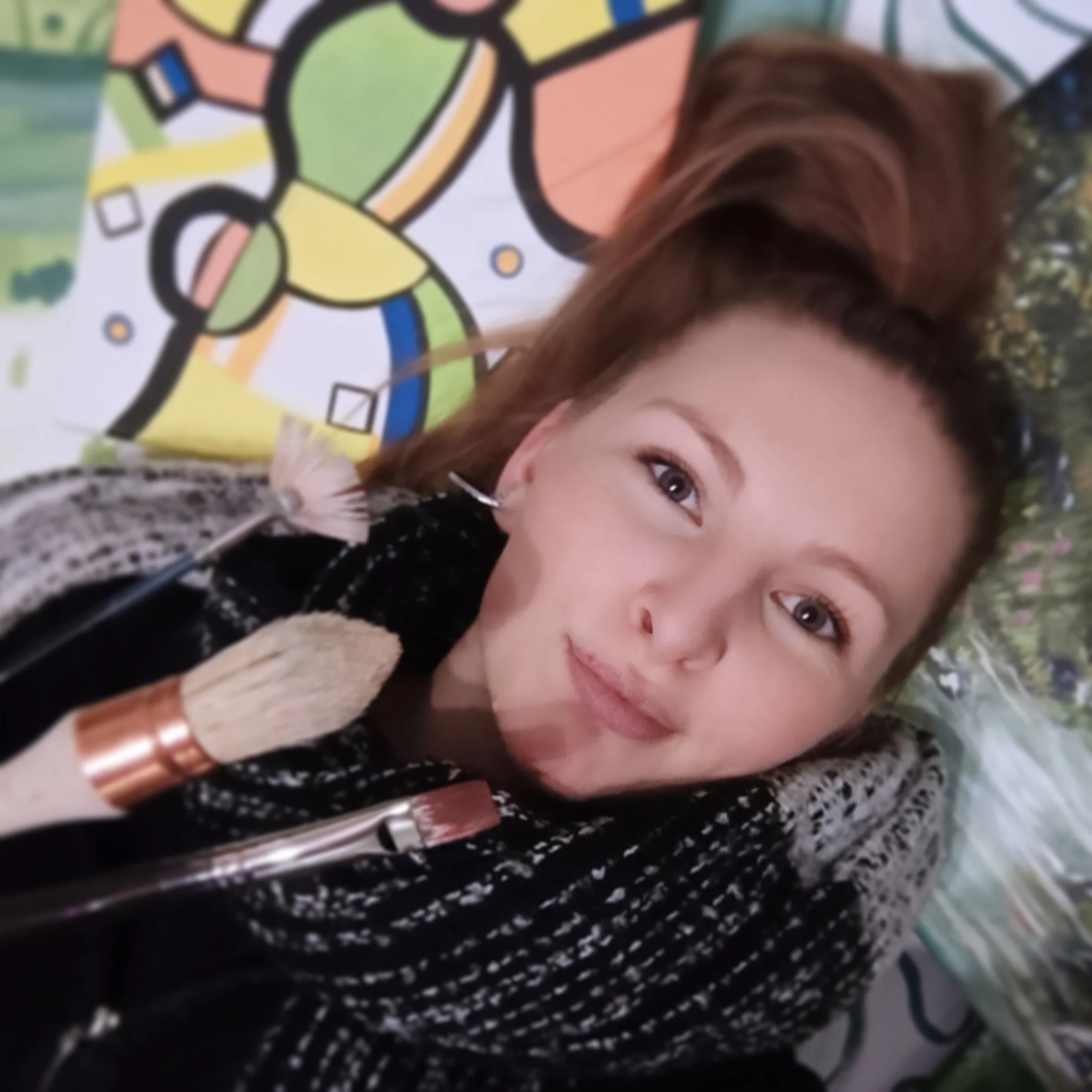 Teil eines Gesichts mit braunen Haaren und blauen Augen, im Hintergrund bunte, abstrakte Kunst.